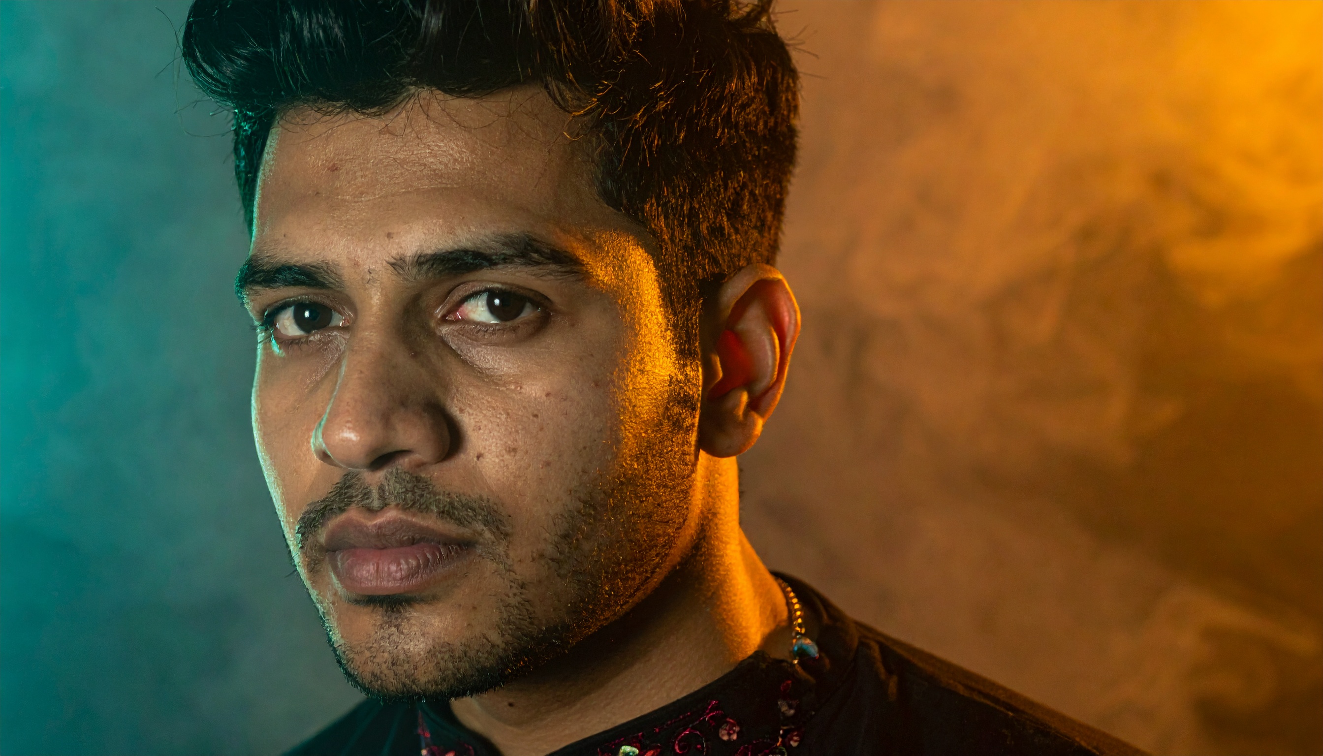 A man gazes intently against a backdrop of warm, diffused lighting