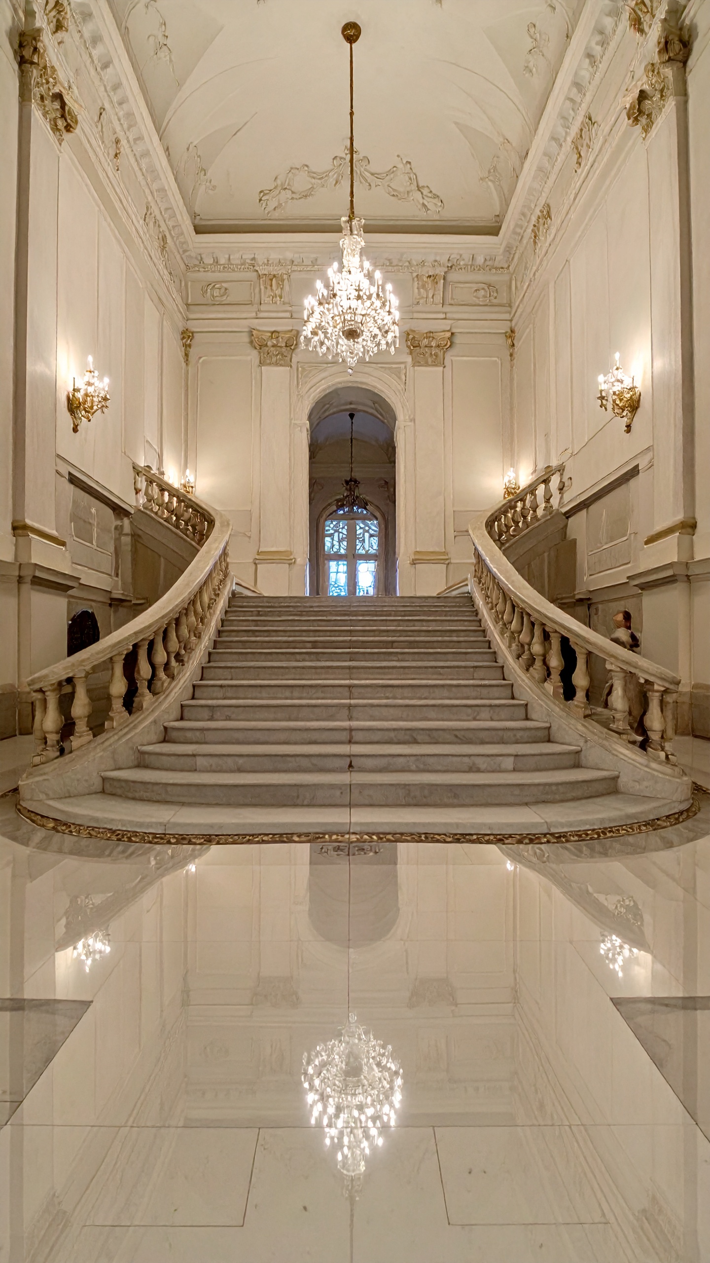 A grand staircase with ornate chandeliers and marble accents