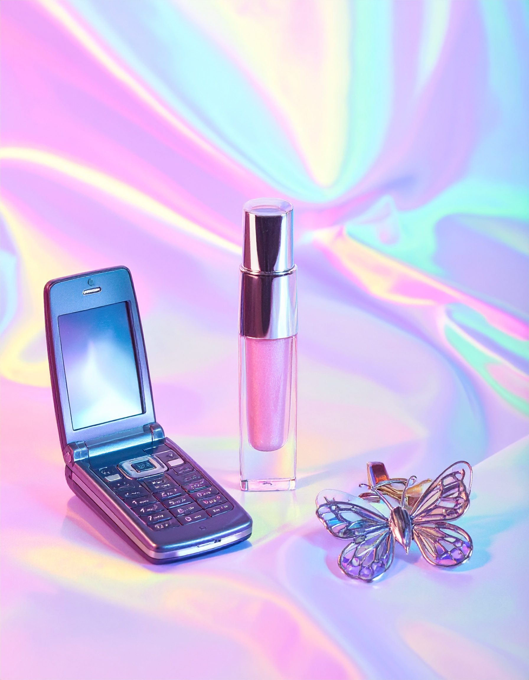 A flip phone, perfume bottle, and butterfly accessory rest on a pastel iridescent background