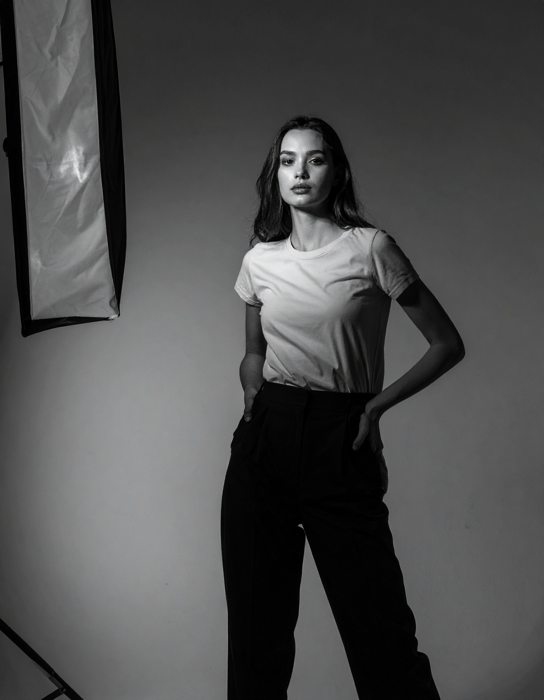 A woman stands confidently in a studio, illuminated by professional lighting