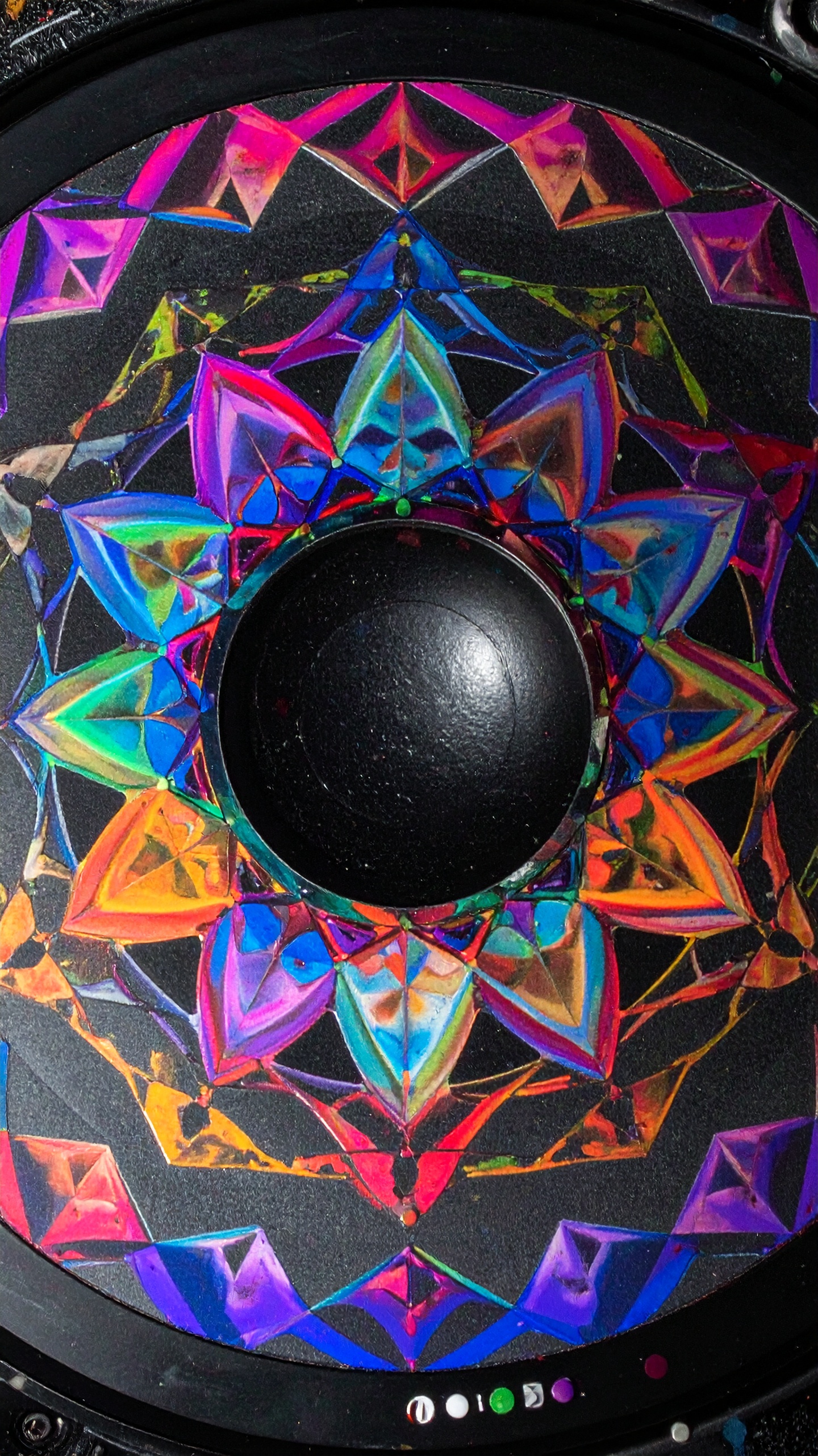 A vibrant speaker with a kaleidoscope design features dynamic geometric patterns in vivid colors