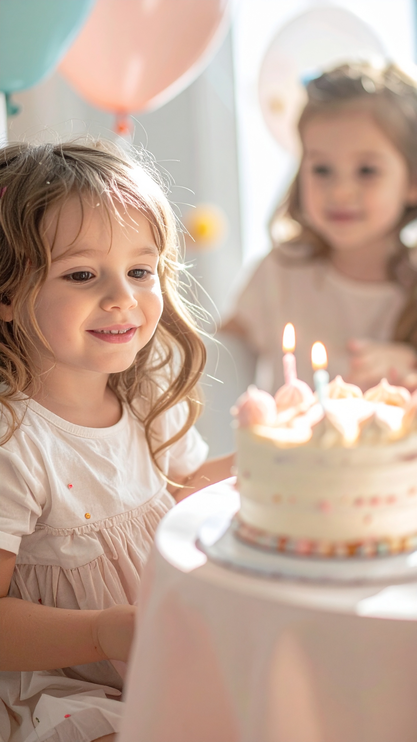 A young girl is joyfully celebrating her birthday with a cake topped with lit candles