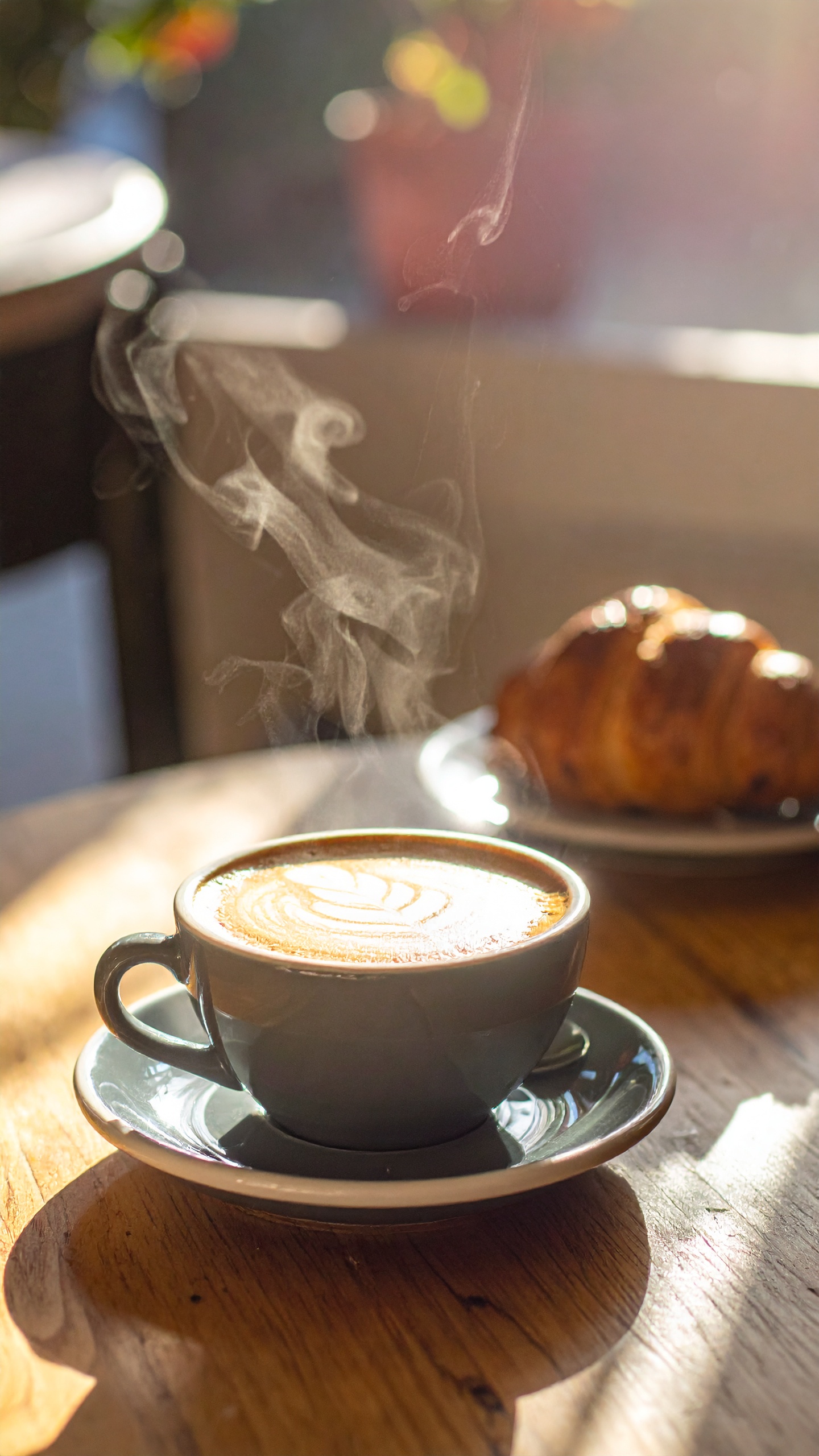 Xícara de café com latte art em ambiente acolhedor e iluminado. Ideal para momentos de relaxamento ou reuniões informais. O vapor que sobe do café em contraste com a luz suave cria uma atmosfera tranquila e convidativa. Perfeito para cafeterias ou ambientes de trabalho criativos que buscam um toque de conforto. Essa combinação de café e croissant é uma representação clássica de prazer simples.