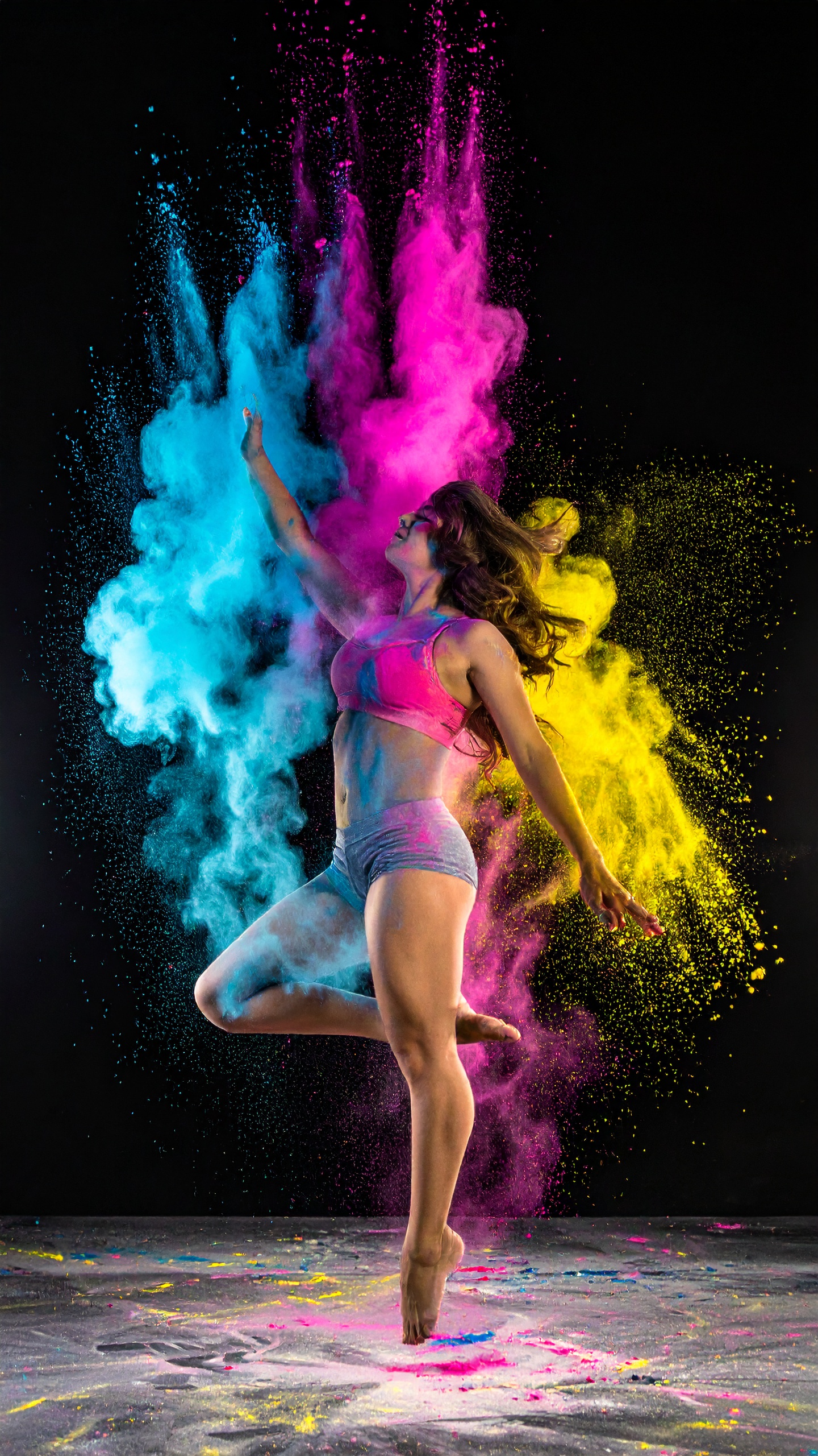 A dynamic dancer leaps through vibrant clouds of colorful powder