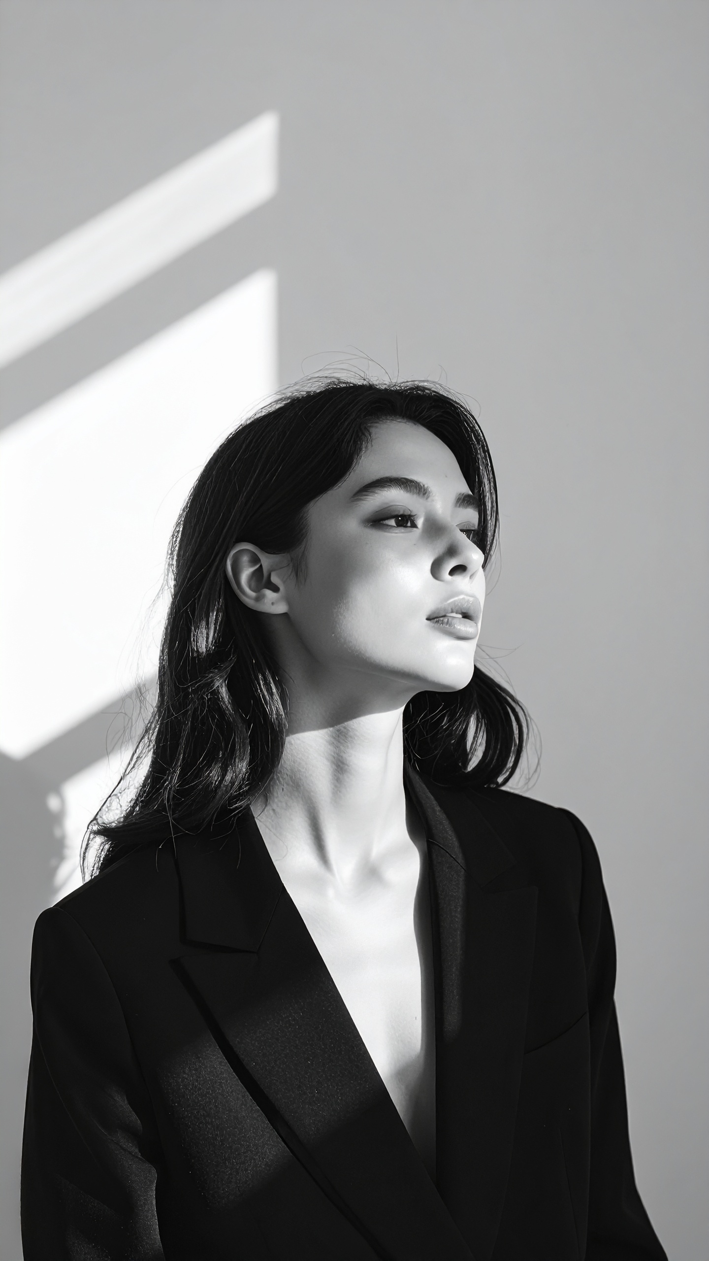 A woman in a black blazer is highlighted by dramatic lighting creating a sophisticated look