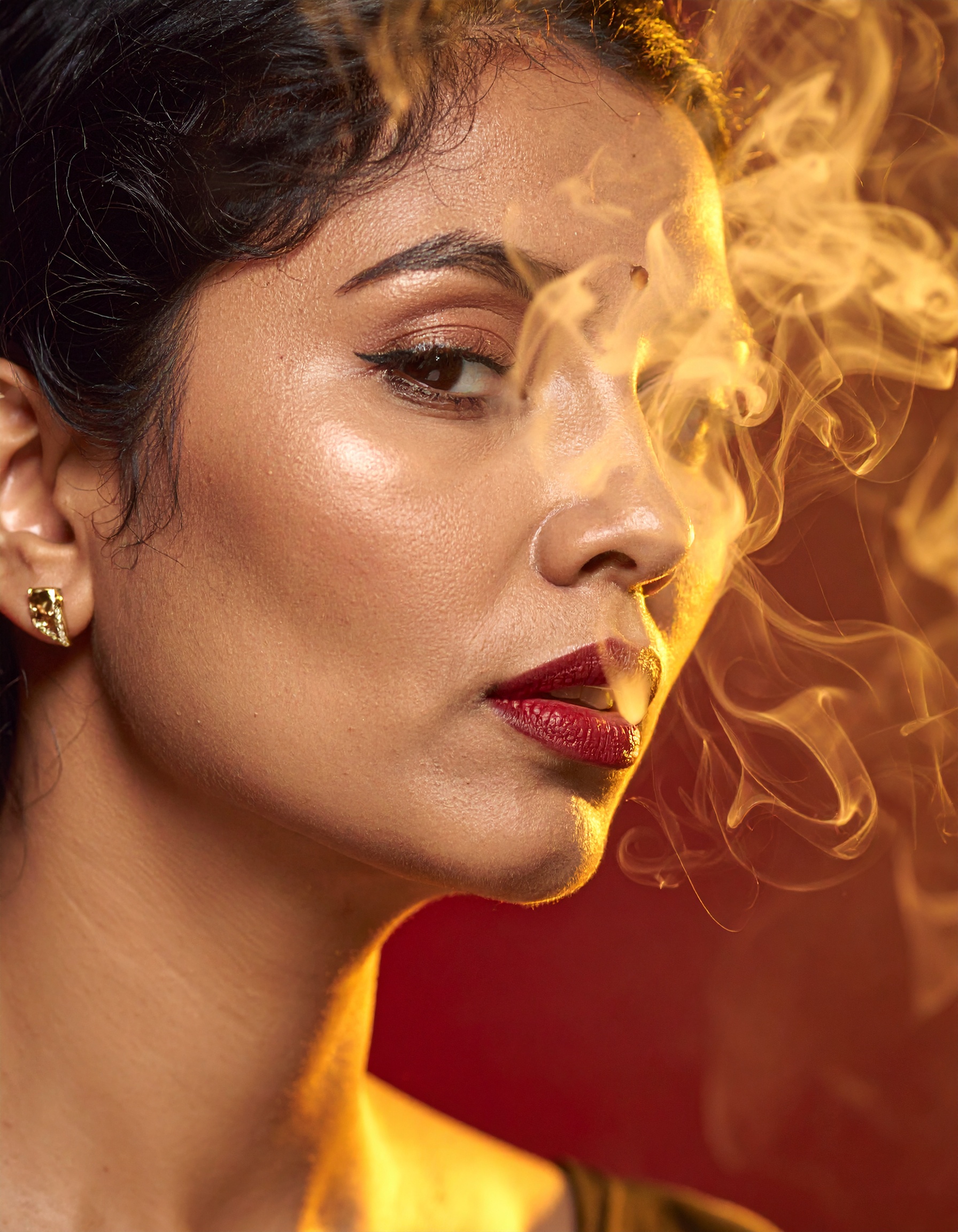 A striking portrait of a woman with dramatic makeup and smoke curling around her face