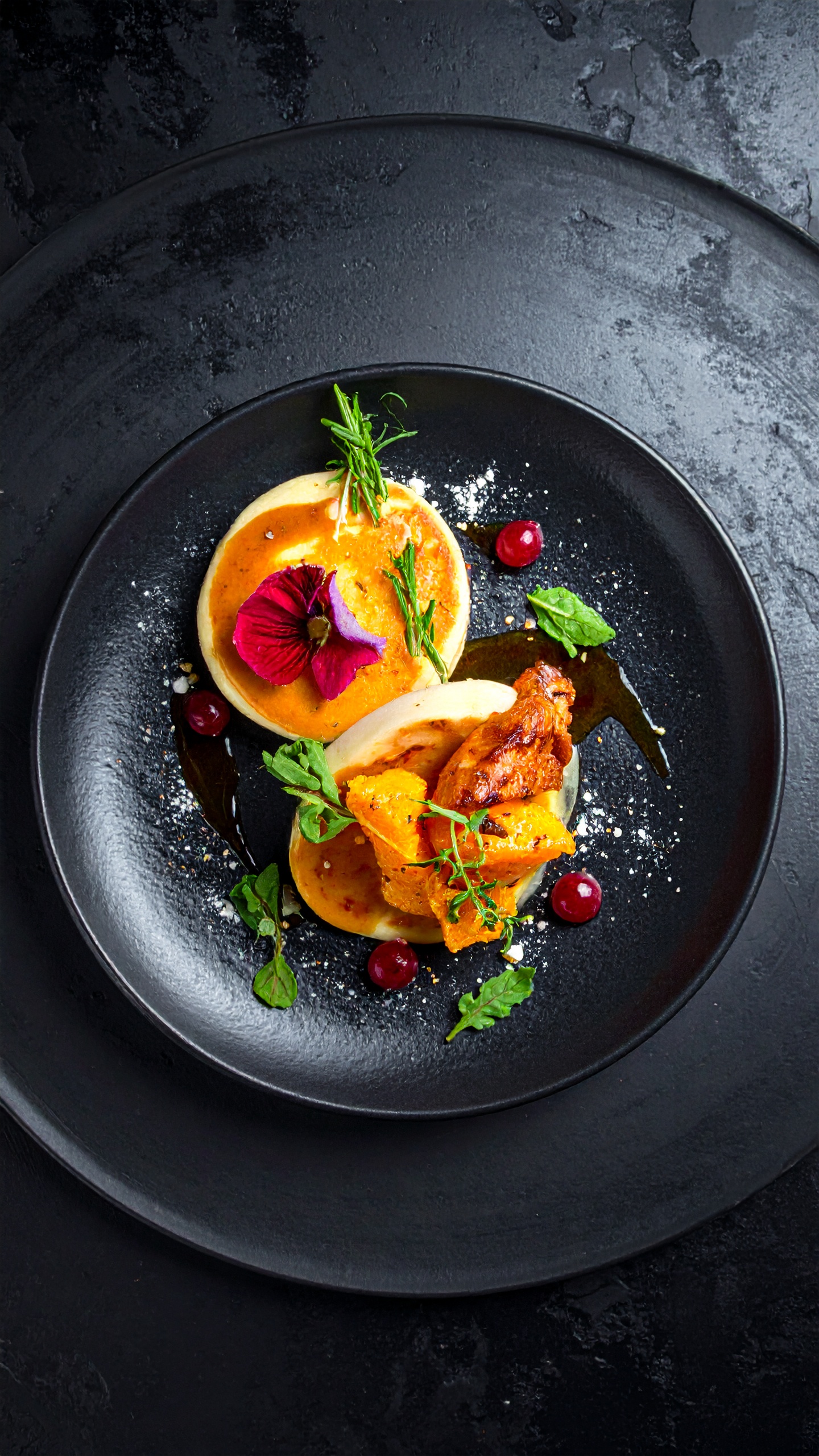 A gourmet dish elegantly presented on a black ceramic plate