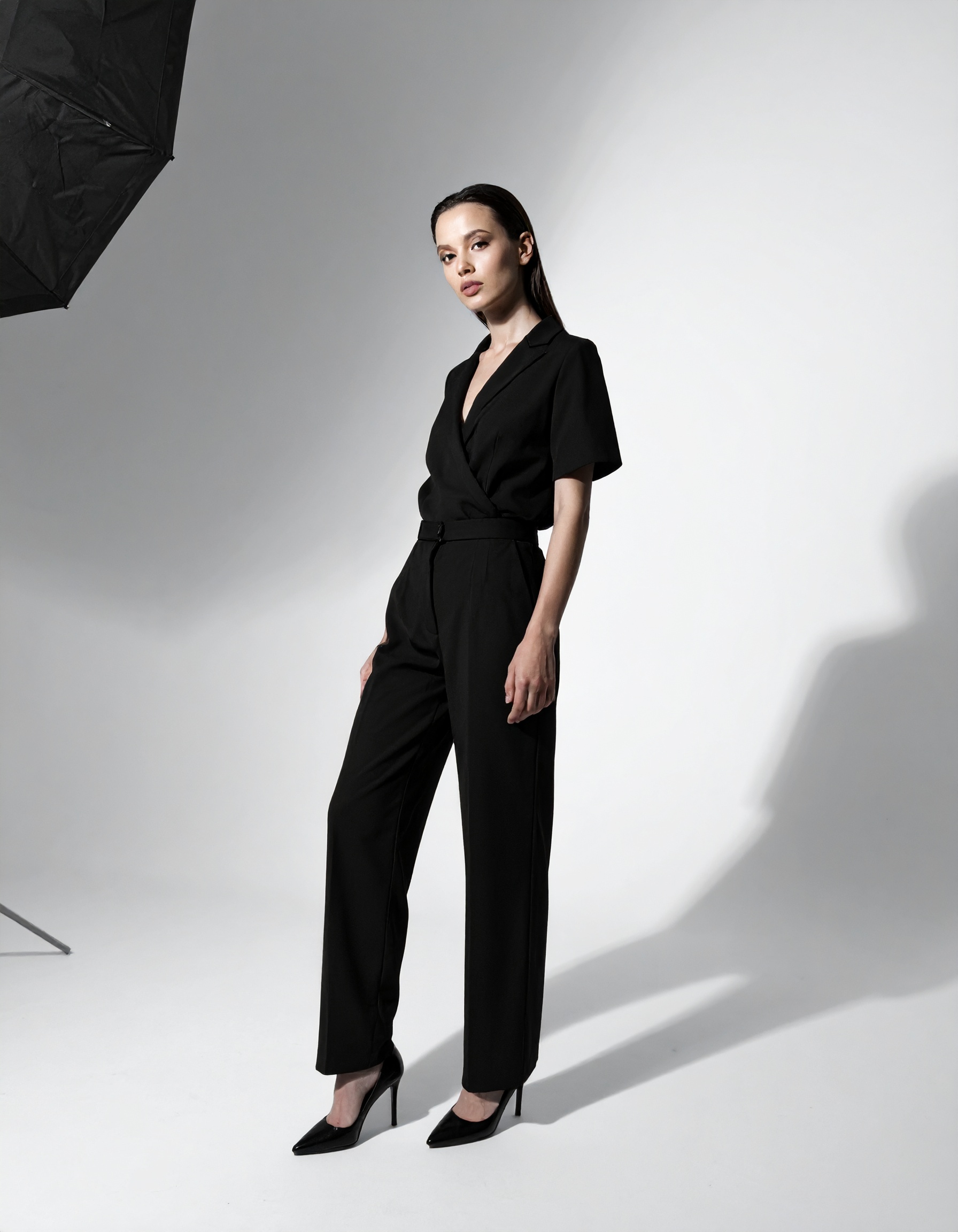 A stylish woman poses confidently in a chic black jumpsuit, perfect for modern professional settings