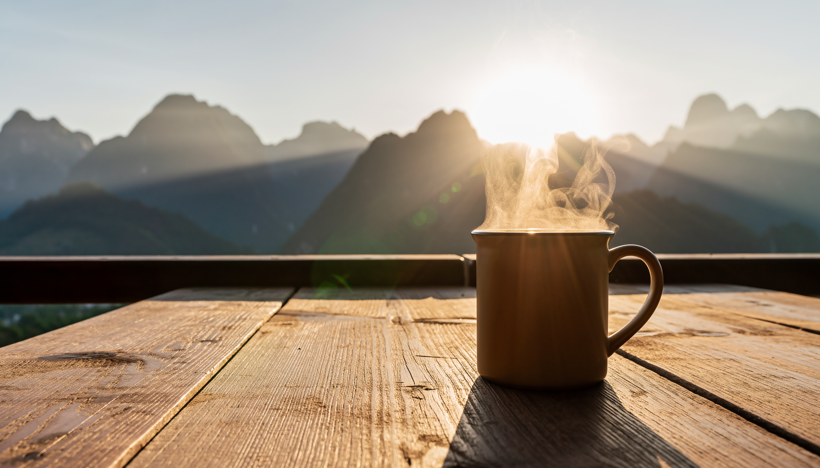 Steaming Mug on Wooden Table at Sunrise