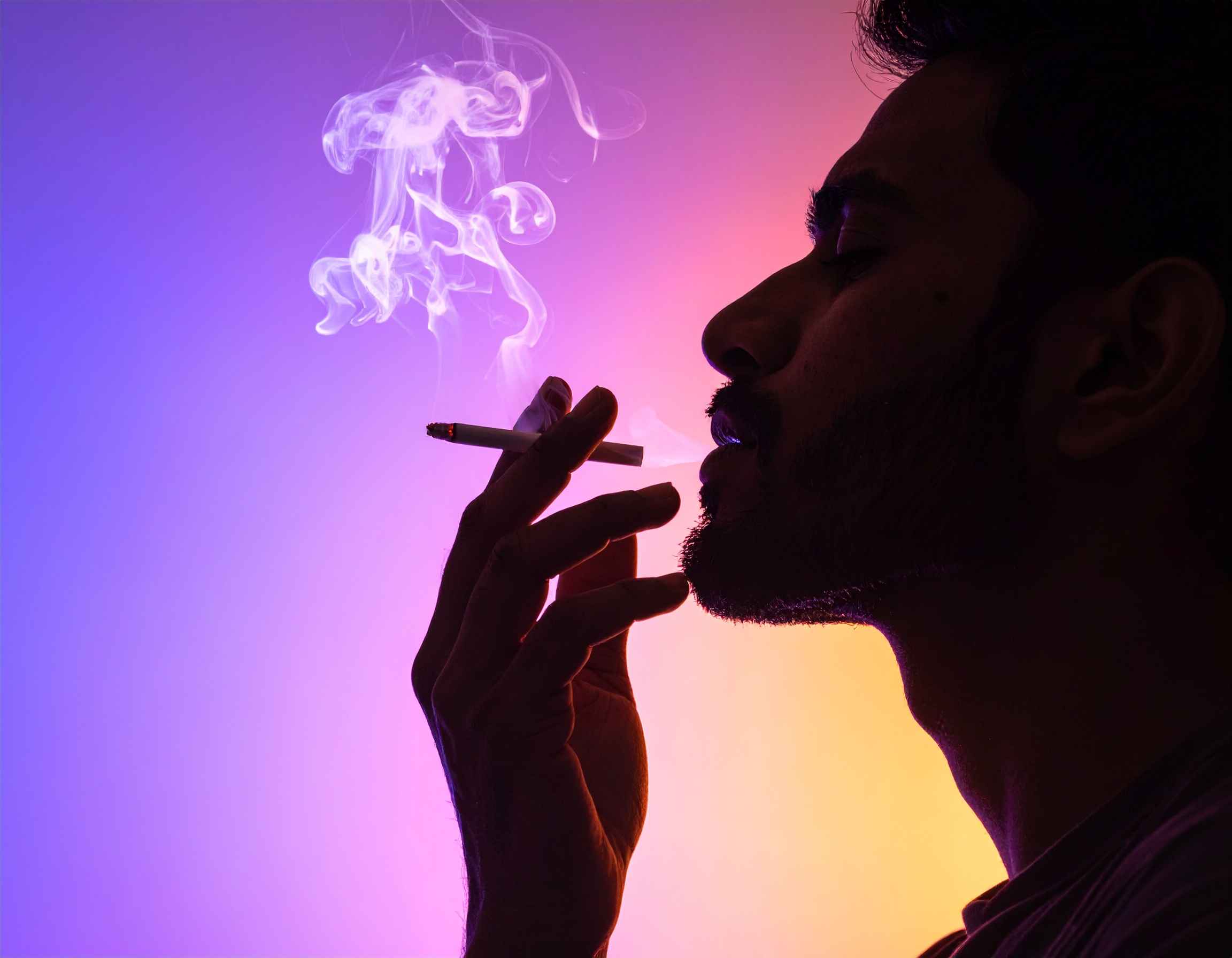 Silhouette of a man smoking against a vibrant gradient background