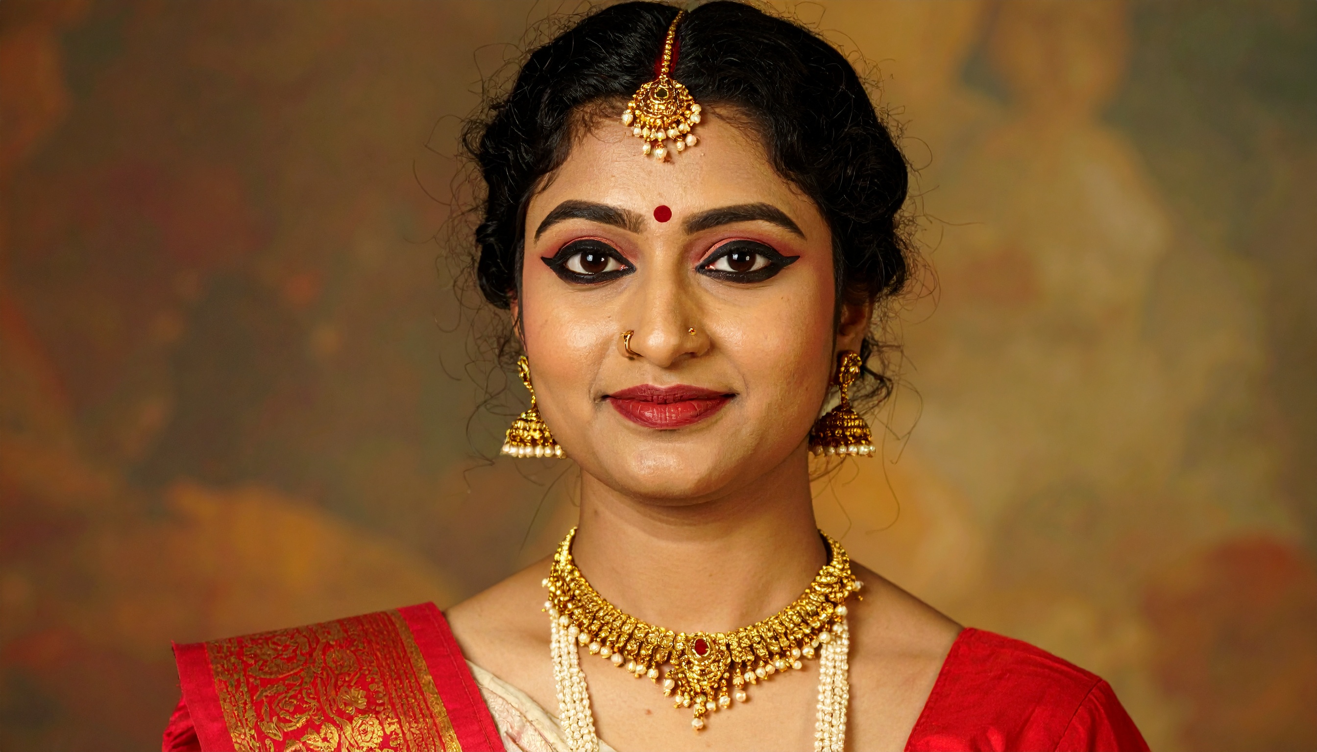 A woman adorned in traditional Indian jewelry and a red saree, showcasing cultural elegance