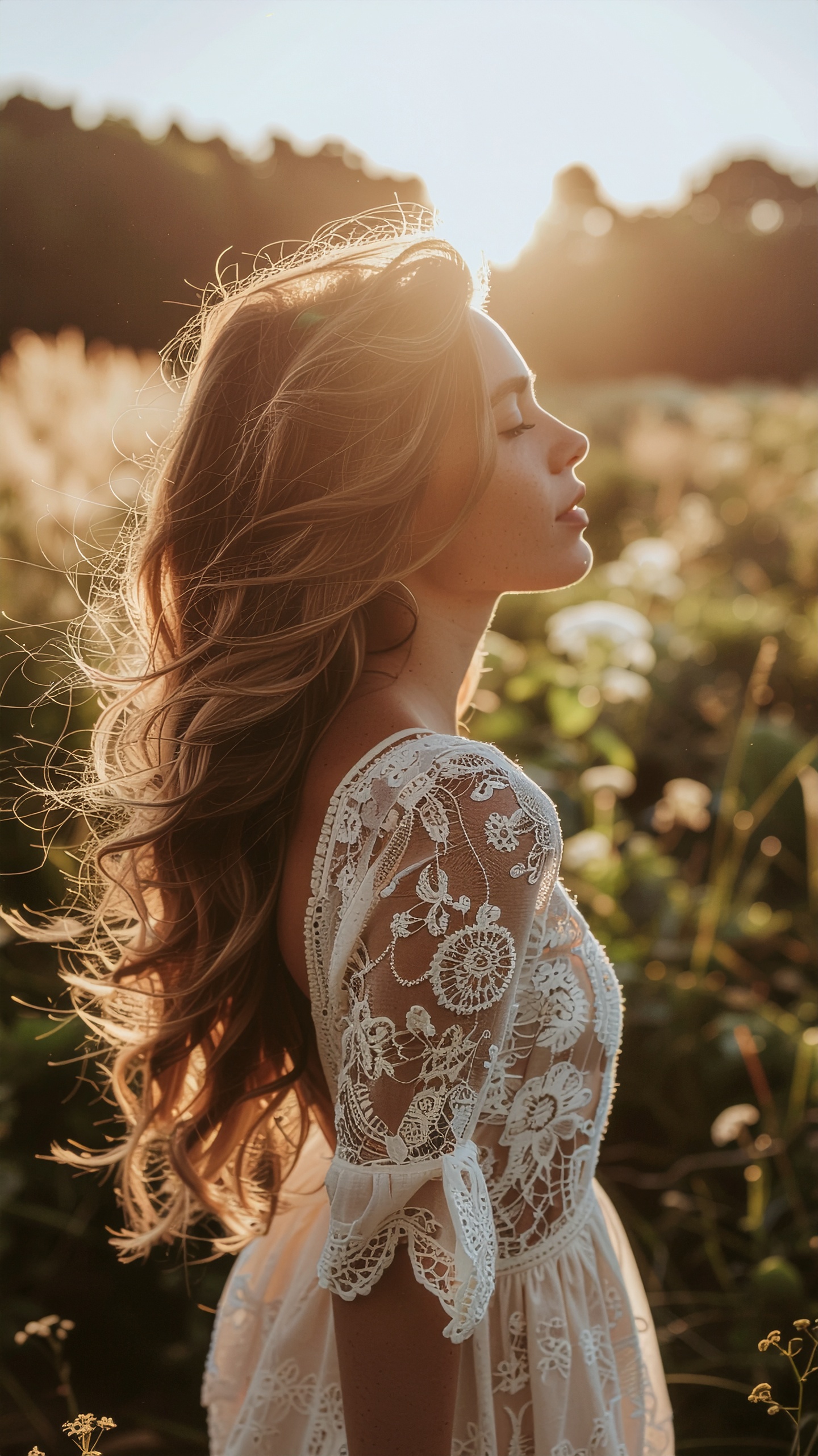 A young woman in a lace dress stands serenely in a sunlit field