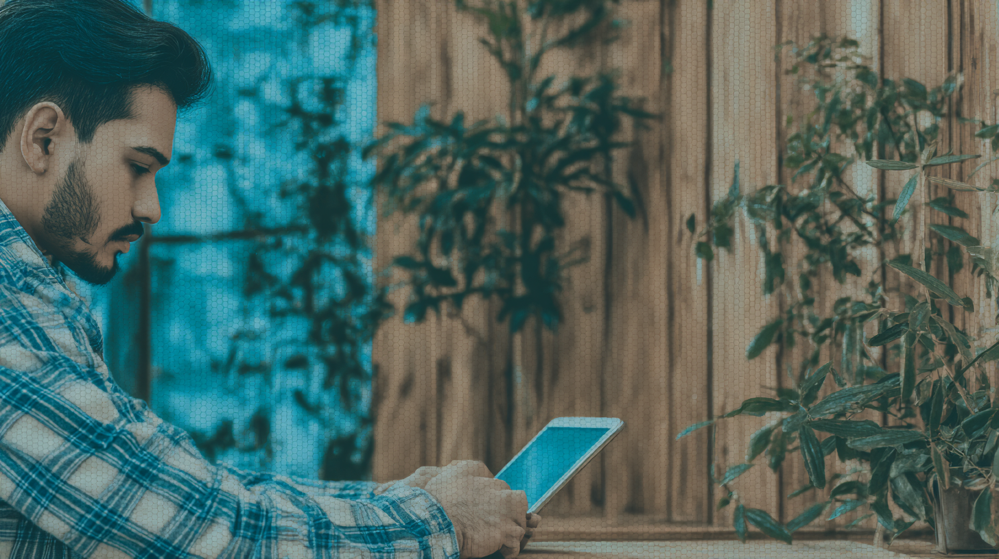Homem de camisa xadrez azul usa tablet em um ambiente externo com plantas ao fundo, iluminação suave e composição equilibrada, criando uma atmosfera tranquila e concentrada.