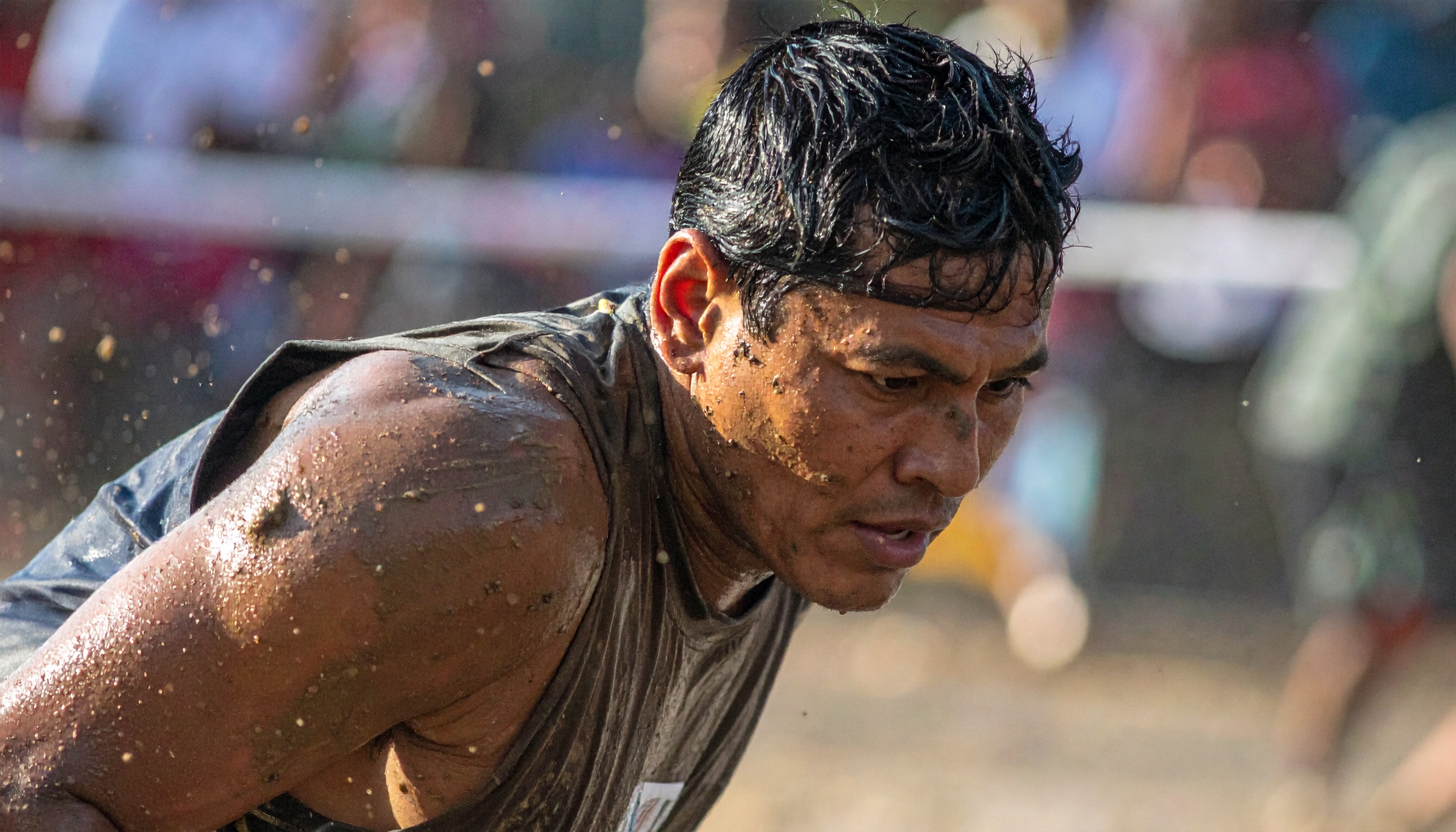 A determined athlete struggles through a muddy obstacle course