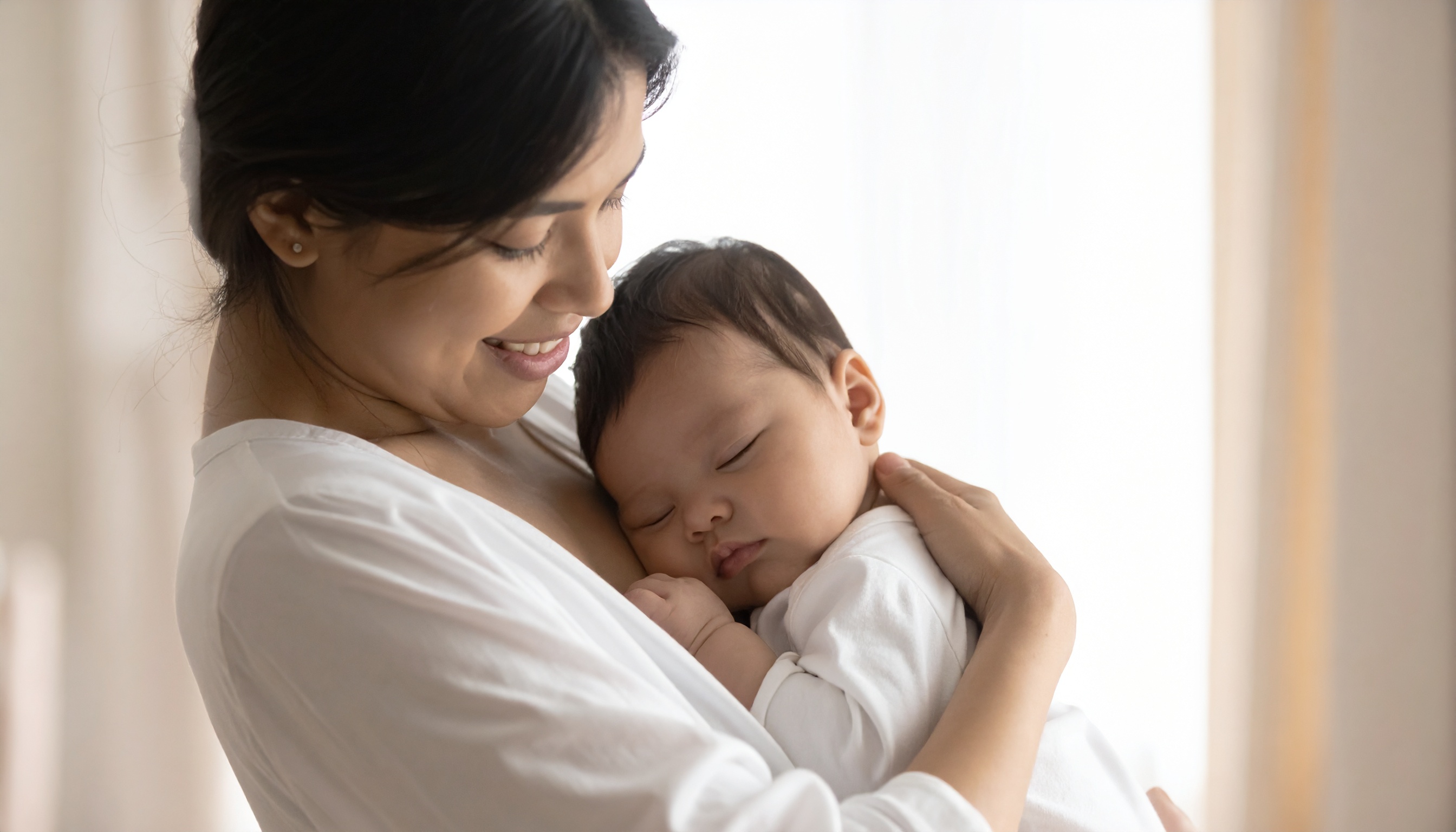 Woman Holding Sleeping Baby in White