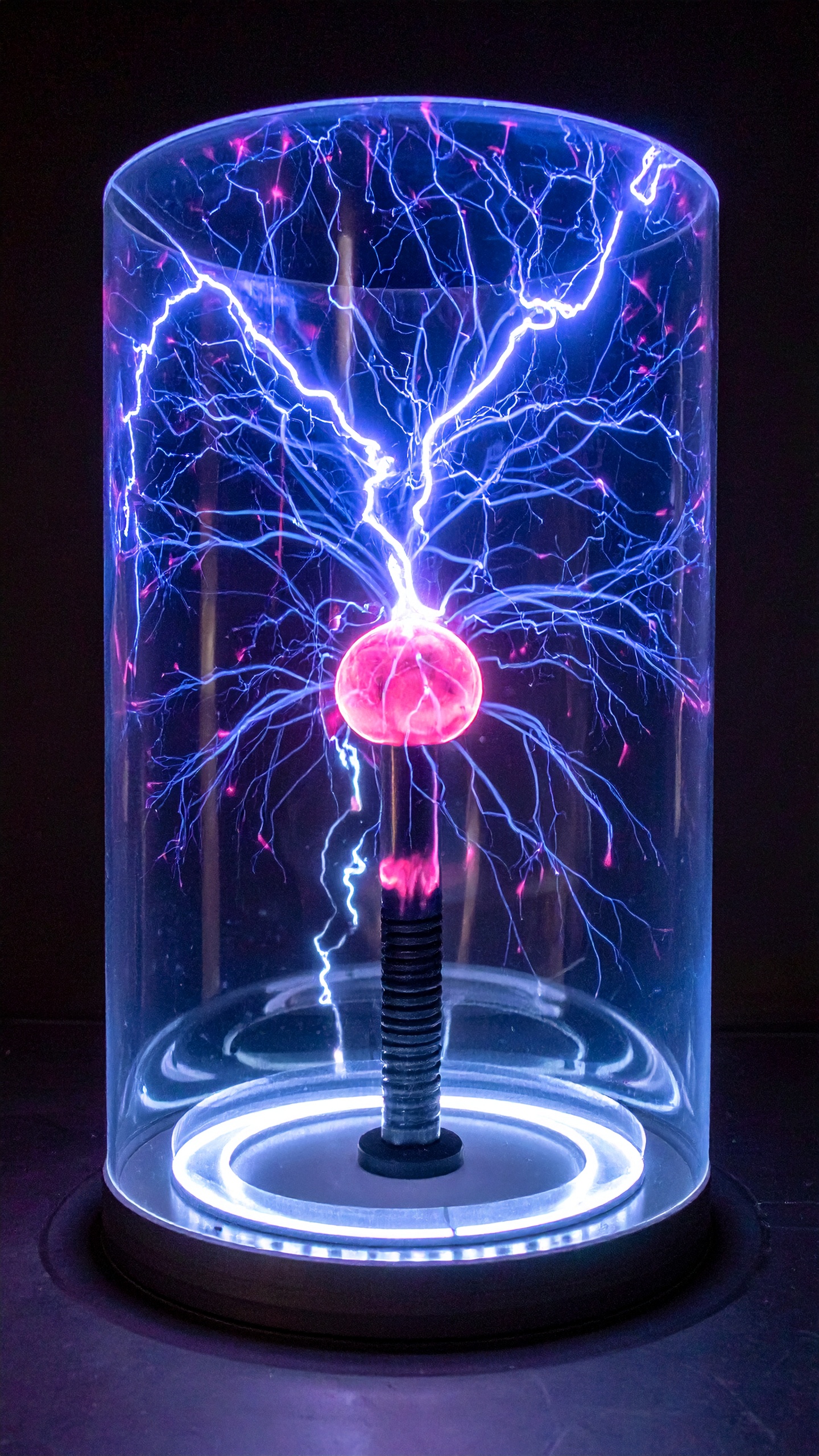 A plasma globe emits vibrant blue and pink lightning-like streams within a clear glass dome