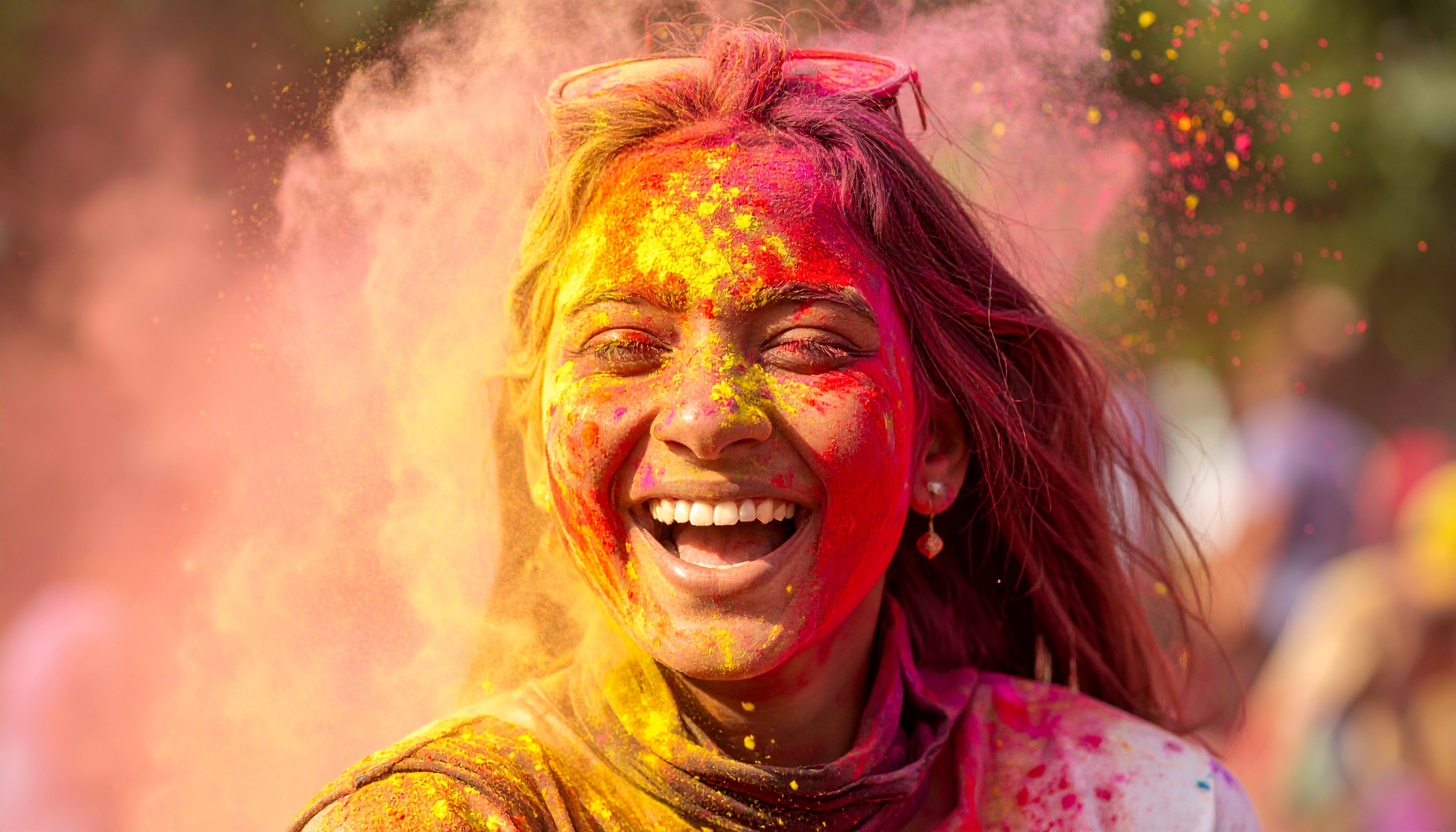 A joyful woman with vibrant colors on her face celebrates at a festival