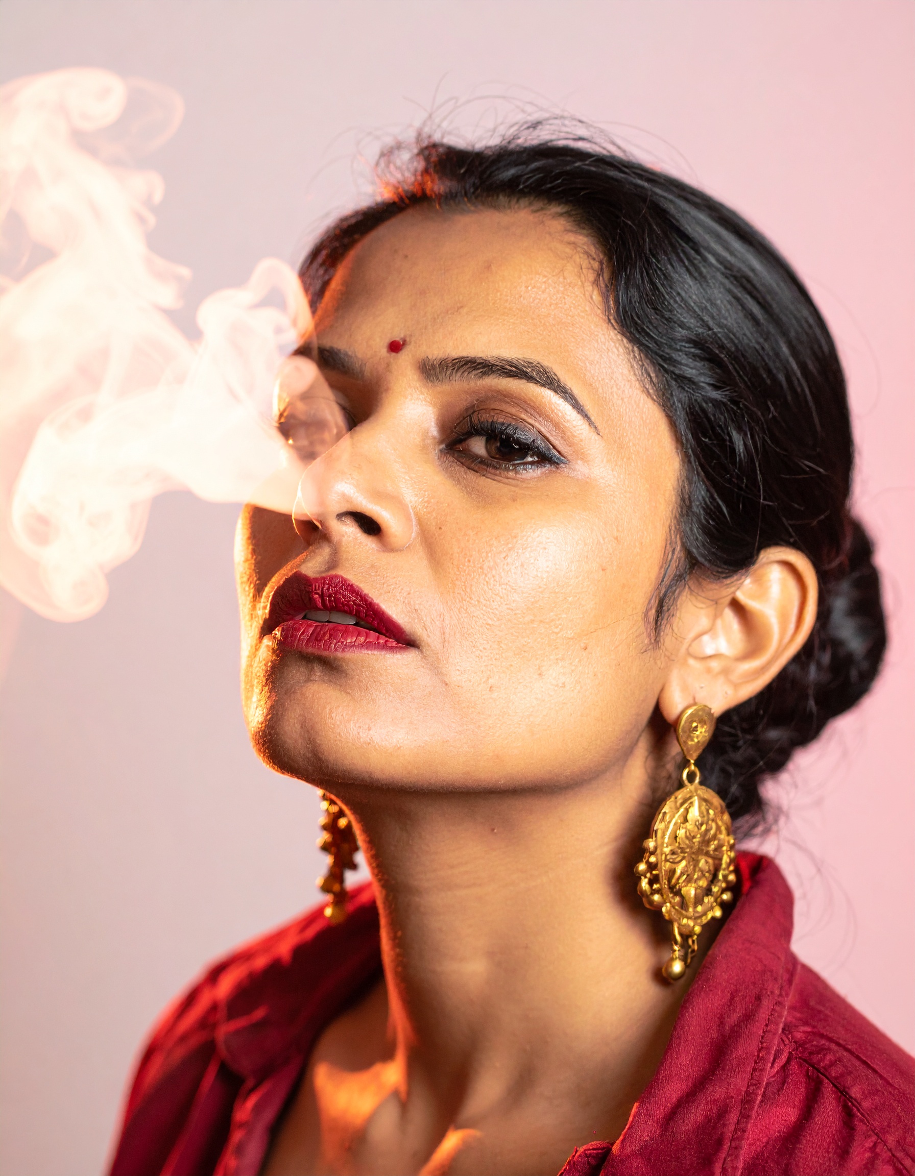 The image features a woman exuding confidence with striking makeup and ornate earrings