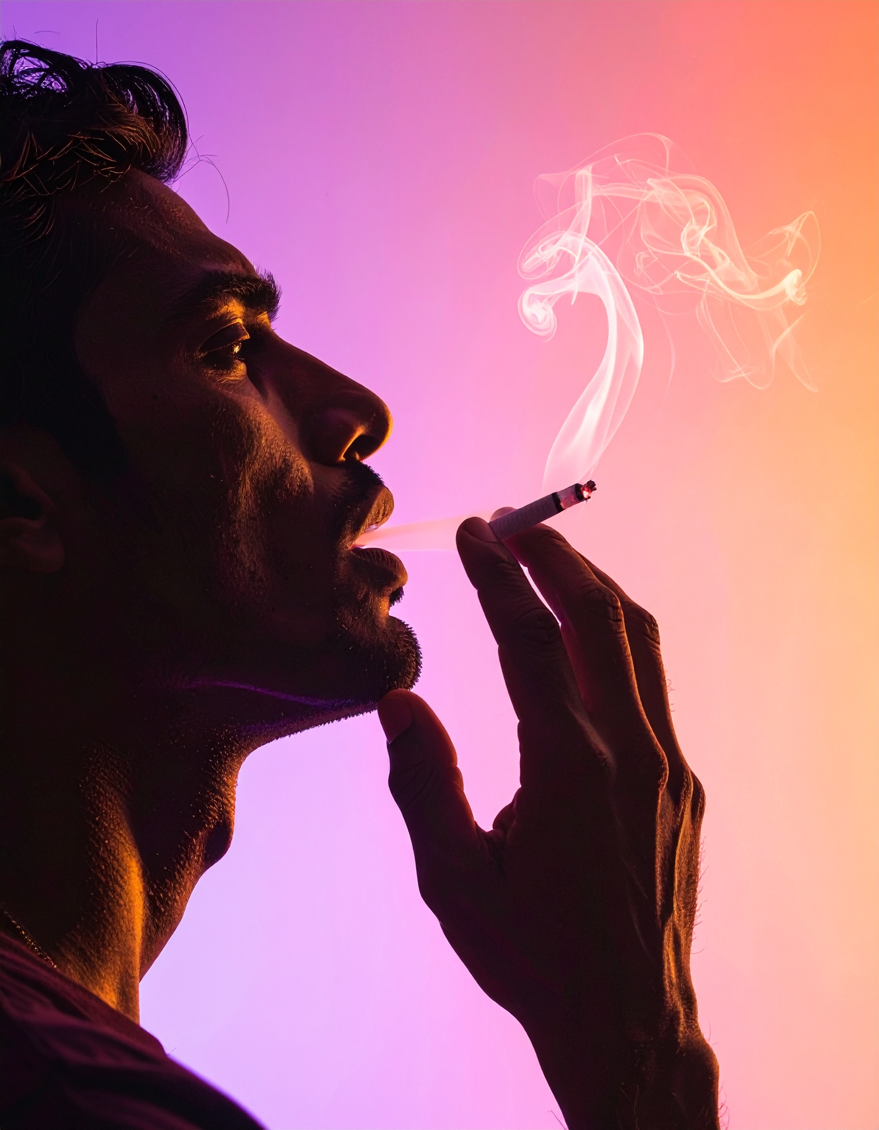 A silhouette of a man smoking against a vibrant gradient background