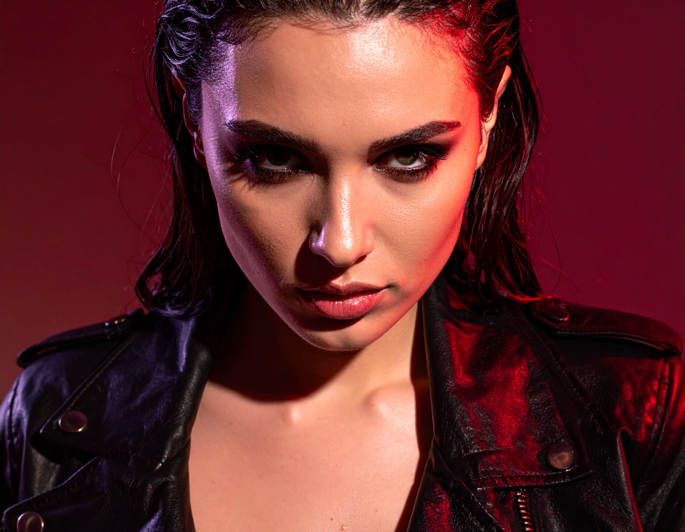 A striking portrait of a person in a black leather jacket against a bold red backdrop