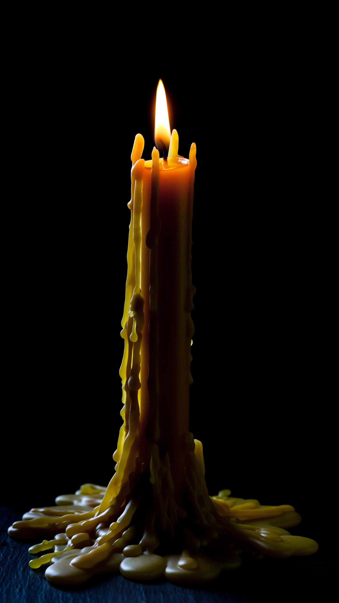 A warm yellow candle burns with a soft glow, casting gentle light