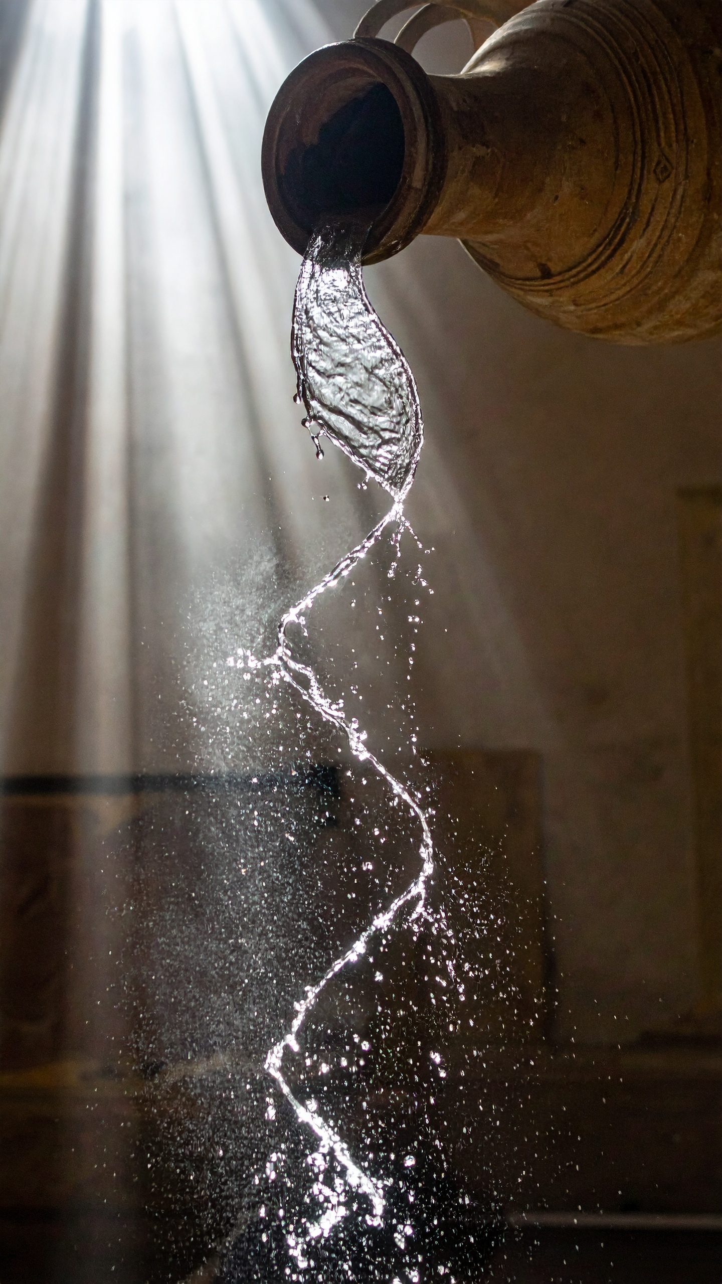 An artisanal clay jug pours water gracefully under a beam of sunlight