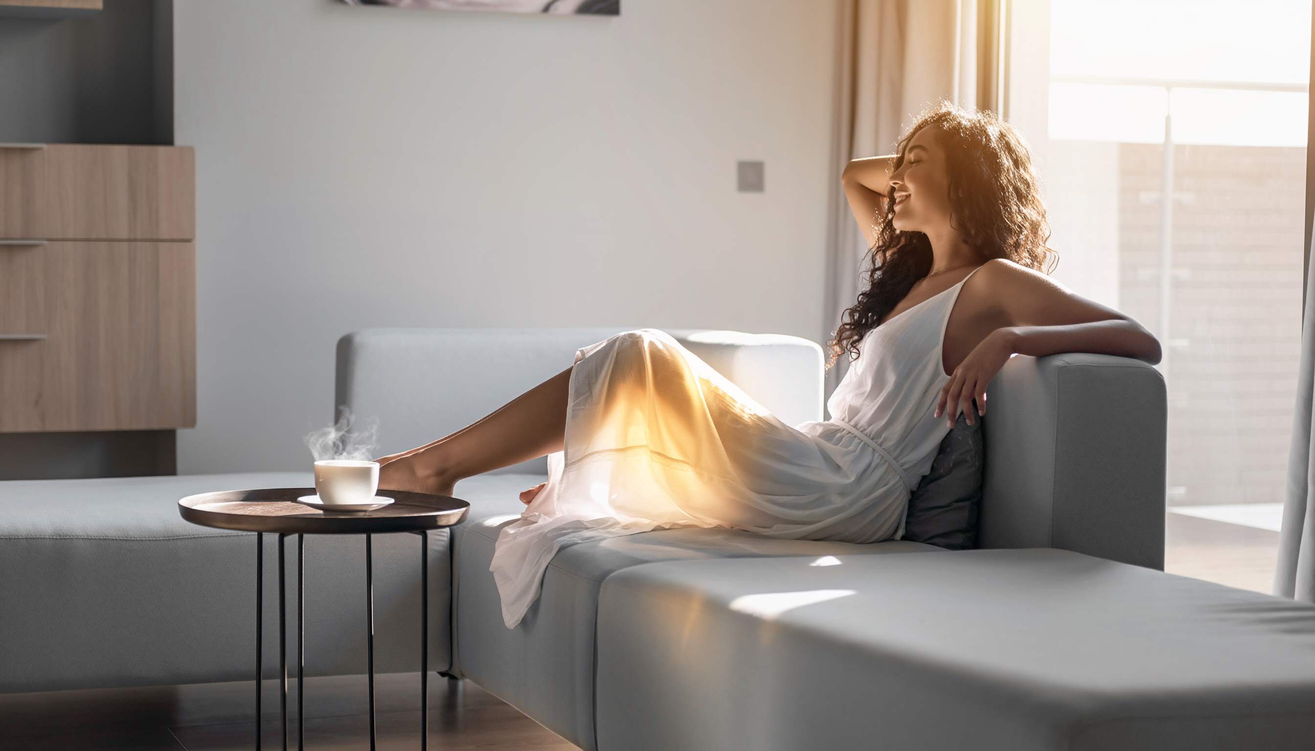 Woman Relaxing on Modern Sofa in Sunlit Room