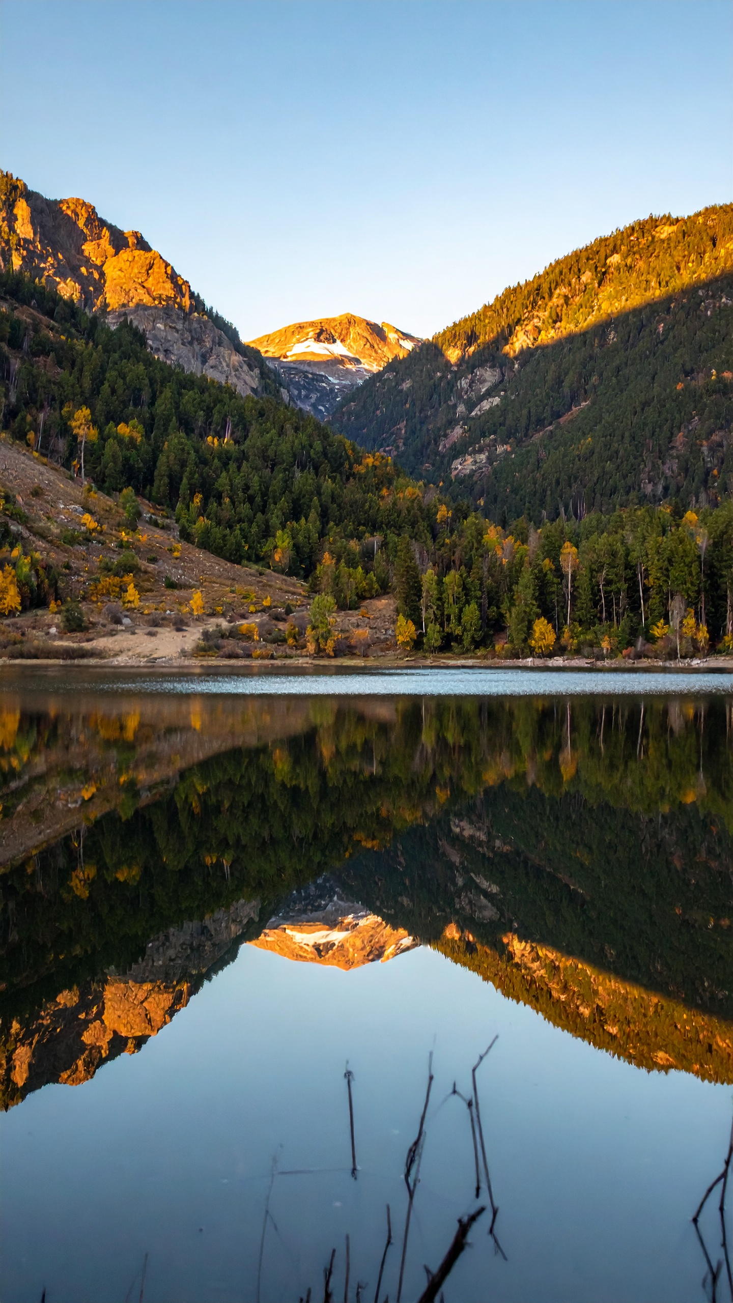A serene mountain landscape reflects in a tranquil lake at sunset