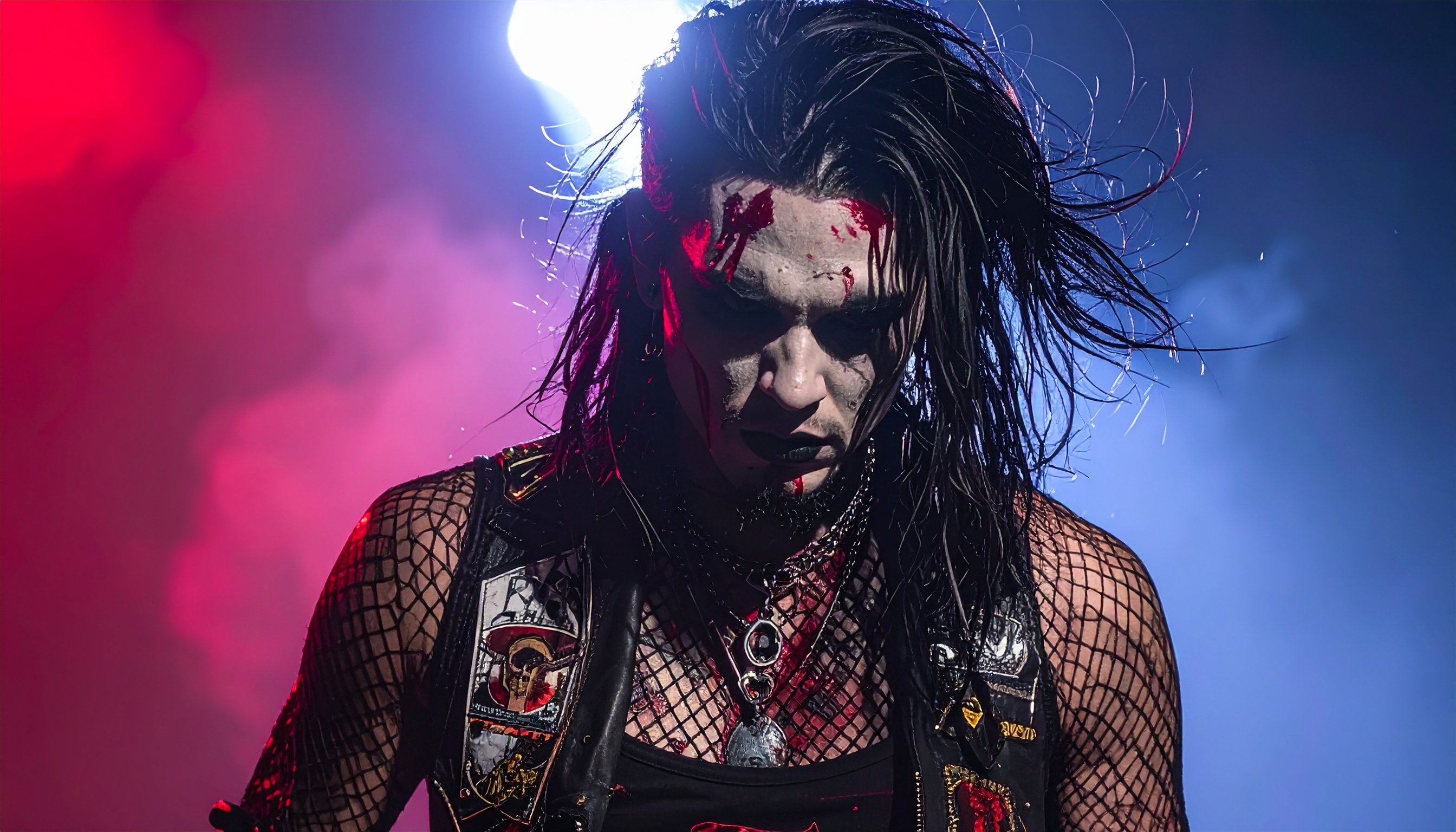 Artista performático com maquiagem dramática em cenário de luzes vibrantes. A imagem capta a essência do estilo gótico, ideal para campanhas de moda alternativa e eventos temáticos. A combinação de luzes vermelhas e azuis cria uma atmosfera intensa e envolvente. Perfeito para promover eventos de Halloween ou festas temáticas. A dramaticidade visual destaca-se para branding em nichos de música e moda alternativa.