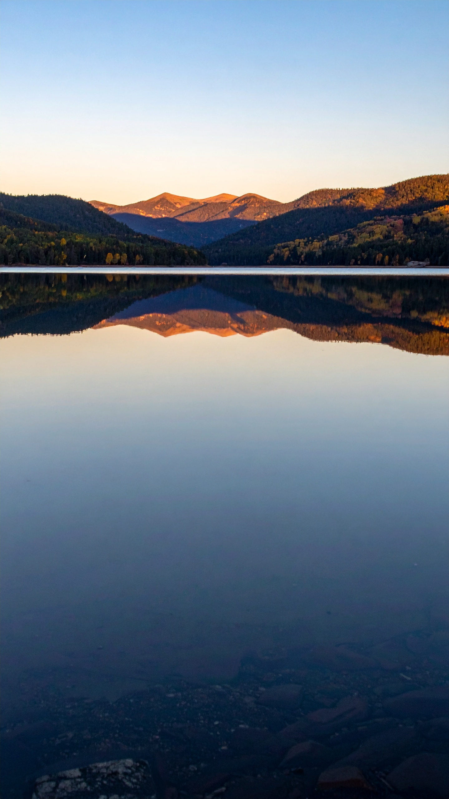 A serene mountain landscape reflected in a still lake at sunset