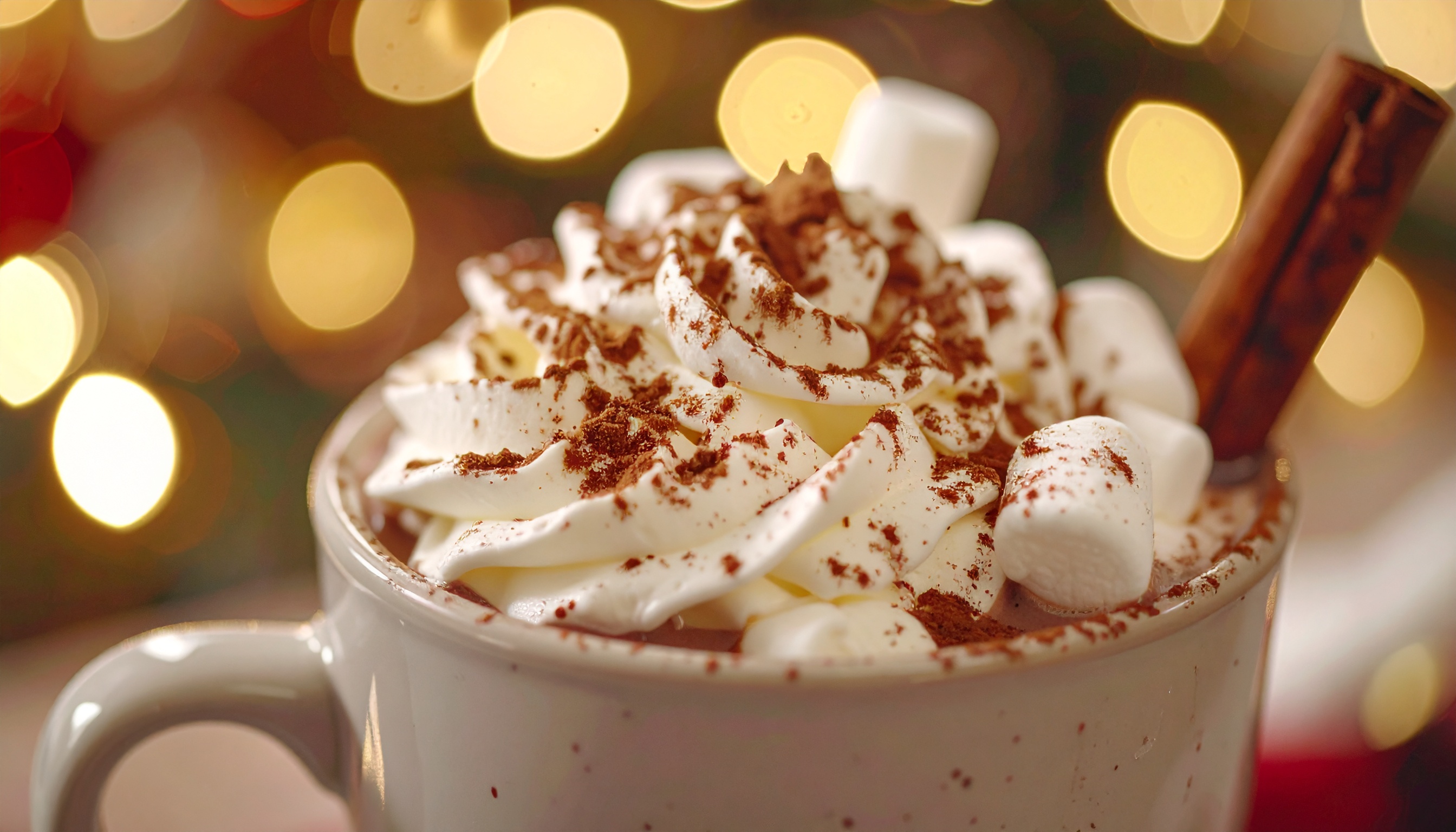 Delicioso chocolate quente coberto com chantilly e polvilhado com cacau, decorado com marshmallows e canela, em uma xícara aconchegante com fundo de luzes de Natal suaves.