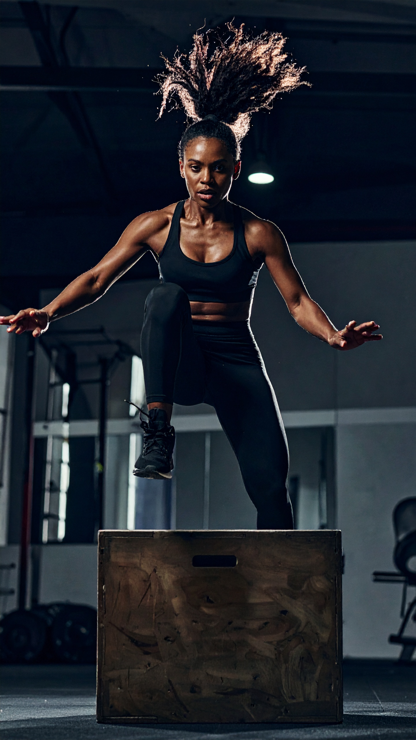 A focused athlete performs a powerful box jump in a gym setting