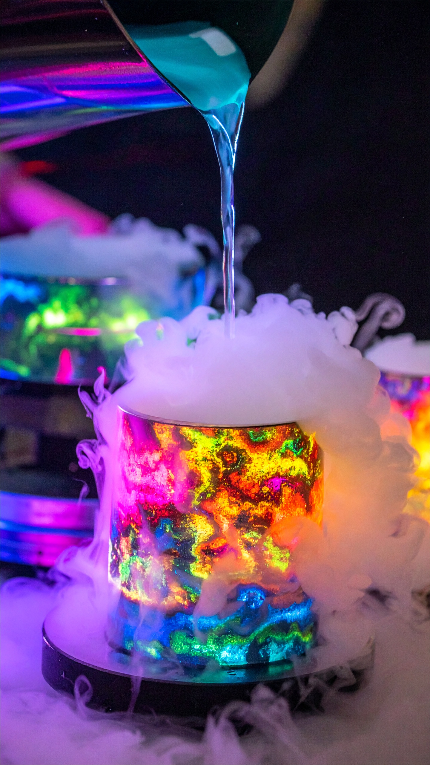 A vibrant cocktail is being poured over a smoking, colorful glass