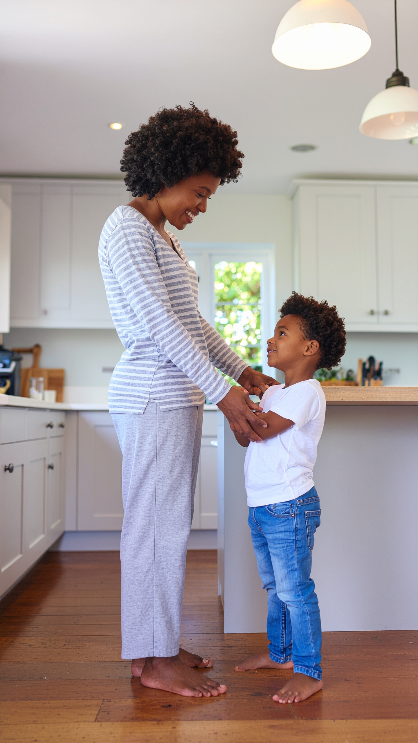 A joyful mother and child stand together in a bright, modern kitchen