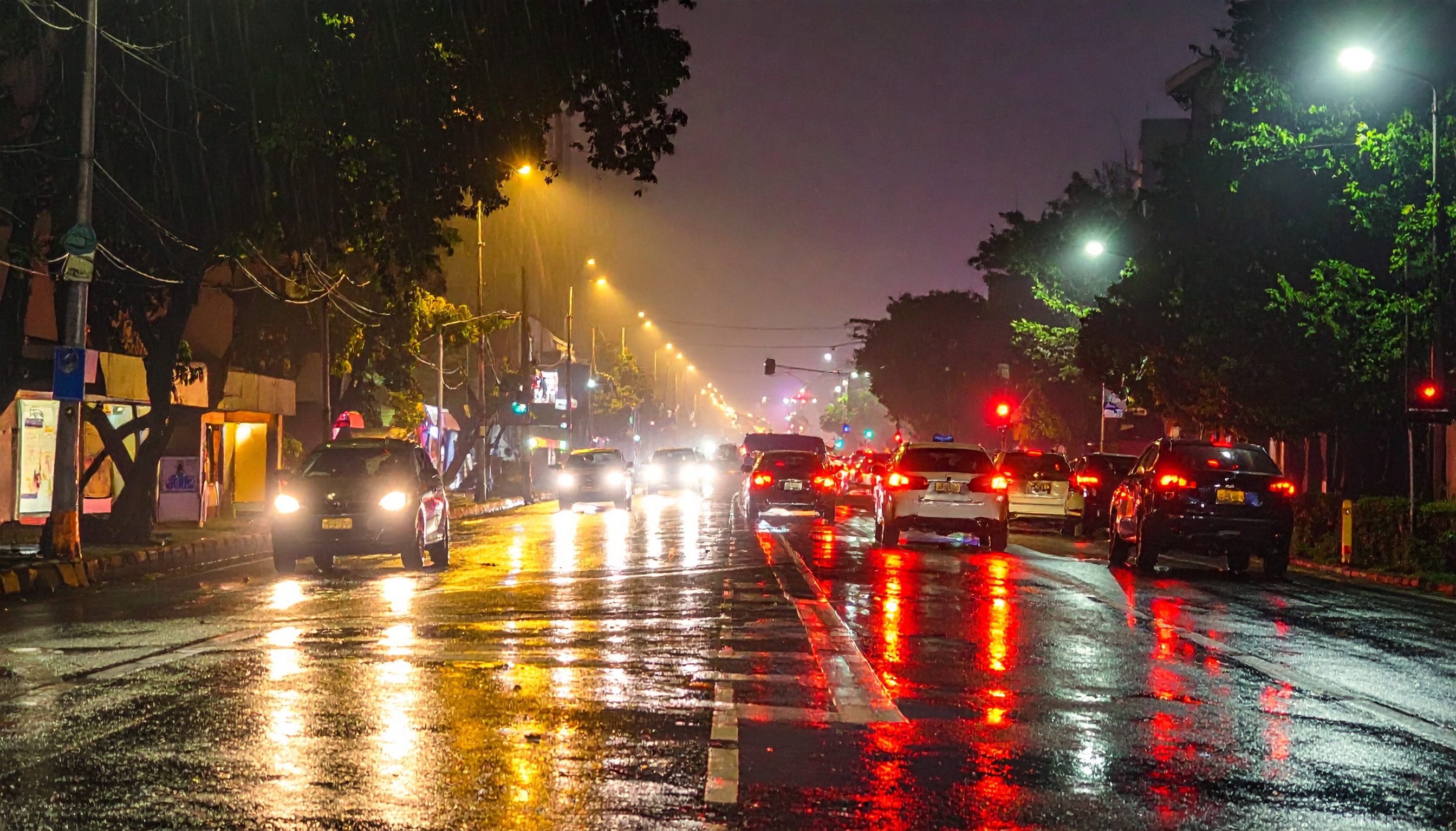 Busy urban street captured at night under glistening rain