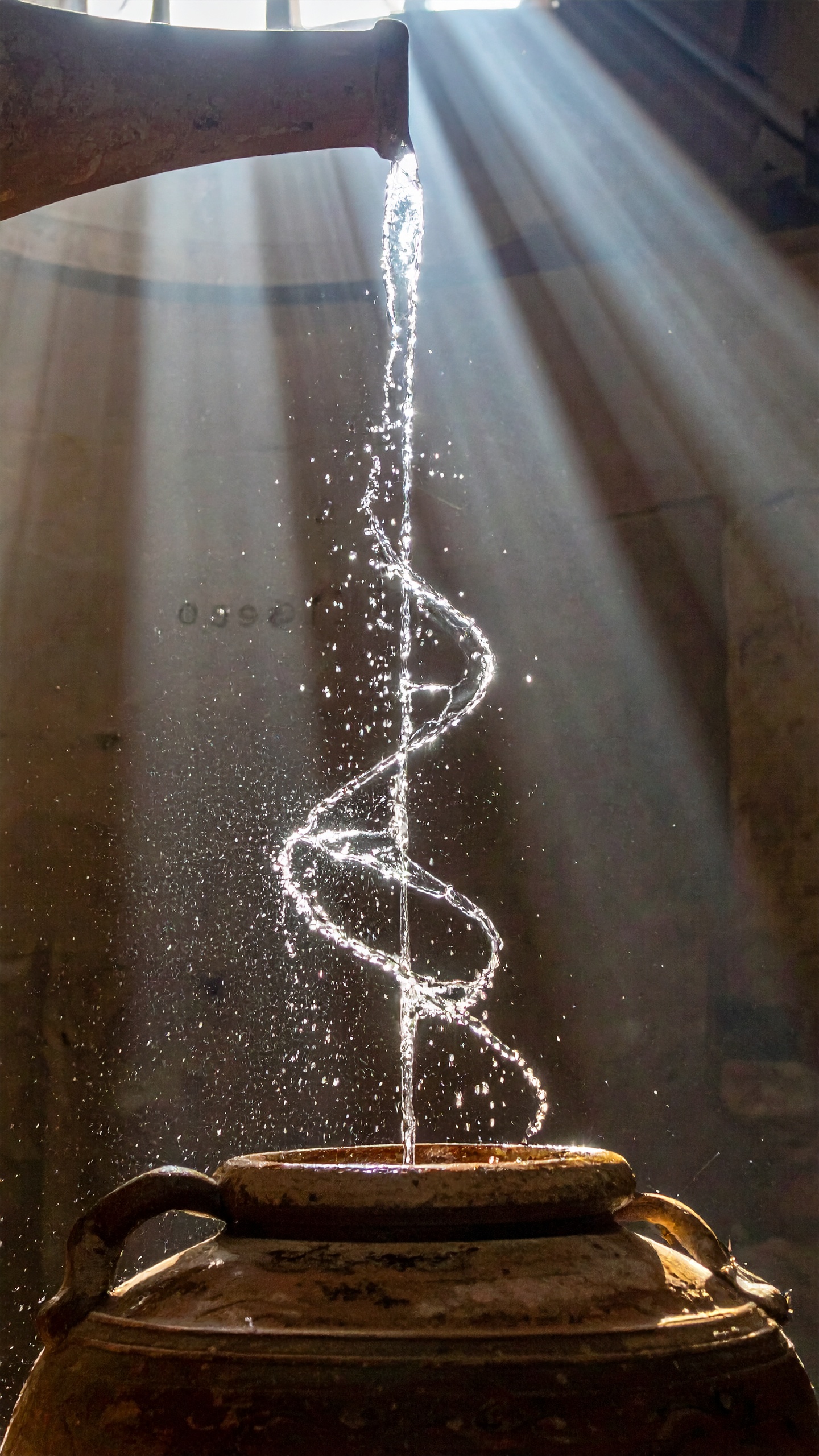 A curved stream of water flows from an ancient clay pot, catching sunlight beautifully