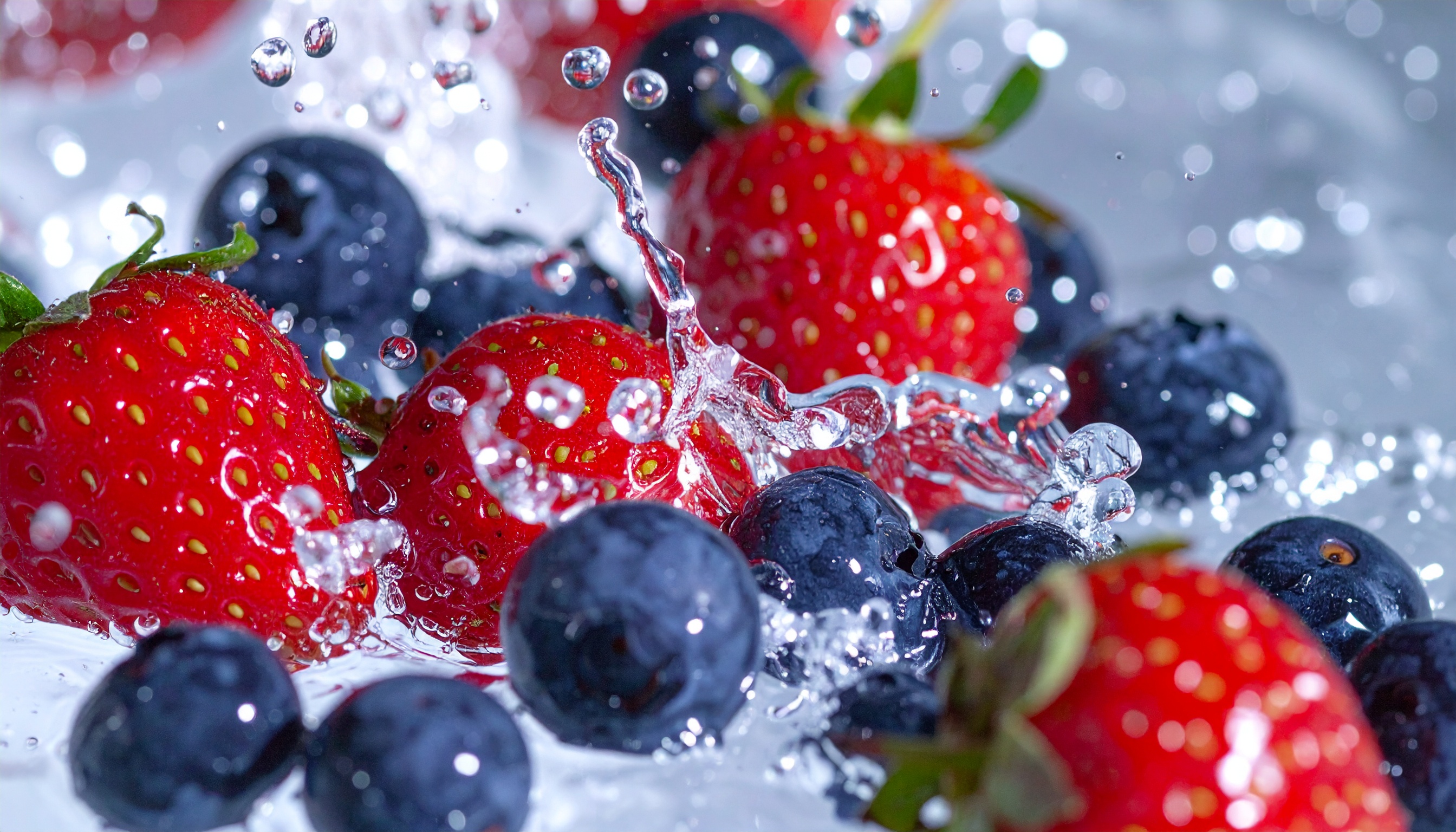 Morangos vermelhos e mirtilos azuis em close-up, com gotas de água cristalinas em movimento, criando um efeito refrescante e vibrante, sob luz intensa.