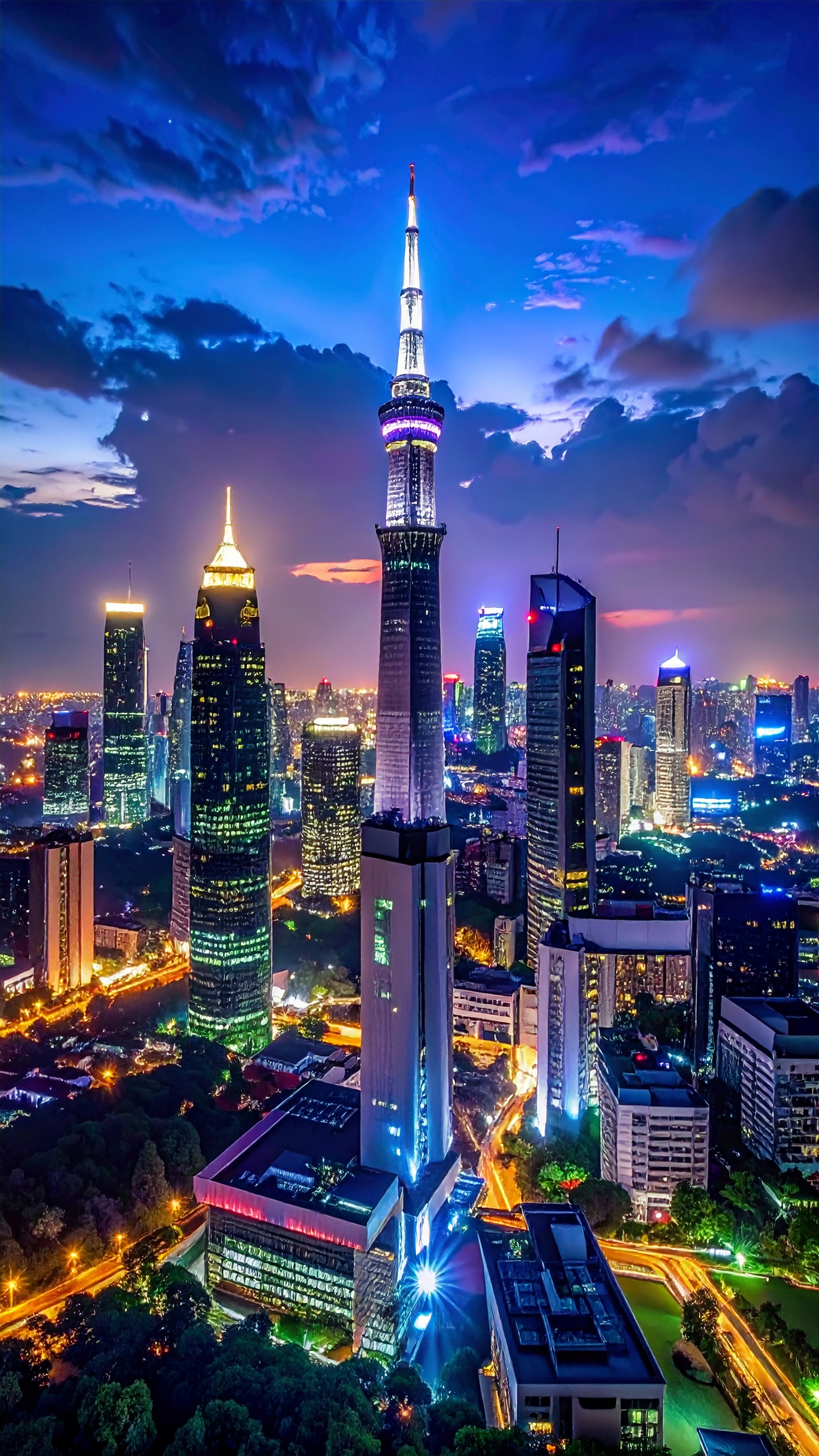 Vista noturna de uma cidade iluminada com arranha-céus imponentes. Ideal para ilustrar modernidade e desenvolvimento urbano, esta imagem captura a vibrante iluminação urbana. Os tons azuis e luzes brilhantes destacam a arquitetura sofisticada dos prédios. Perfeita para campanhas de marketing ligadas a tecnologia ou turismo. A imagem transmite um senso de inovação e dinamismo citadino.