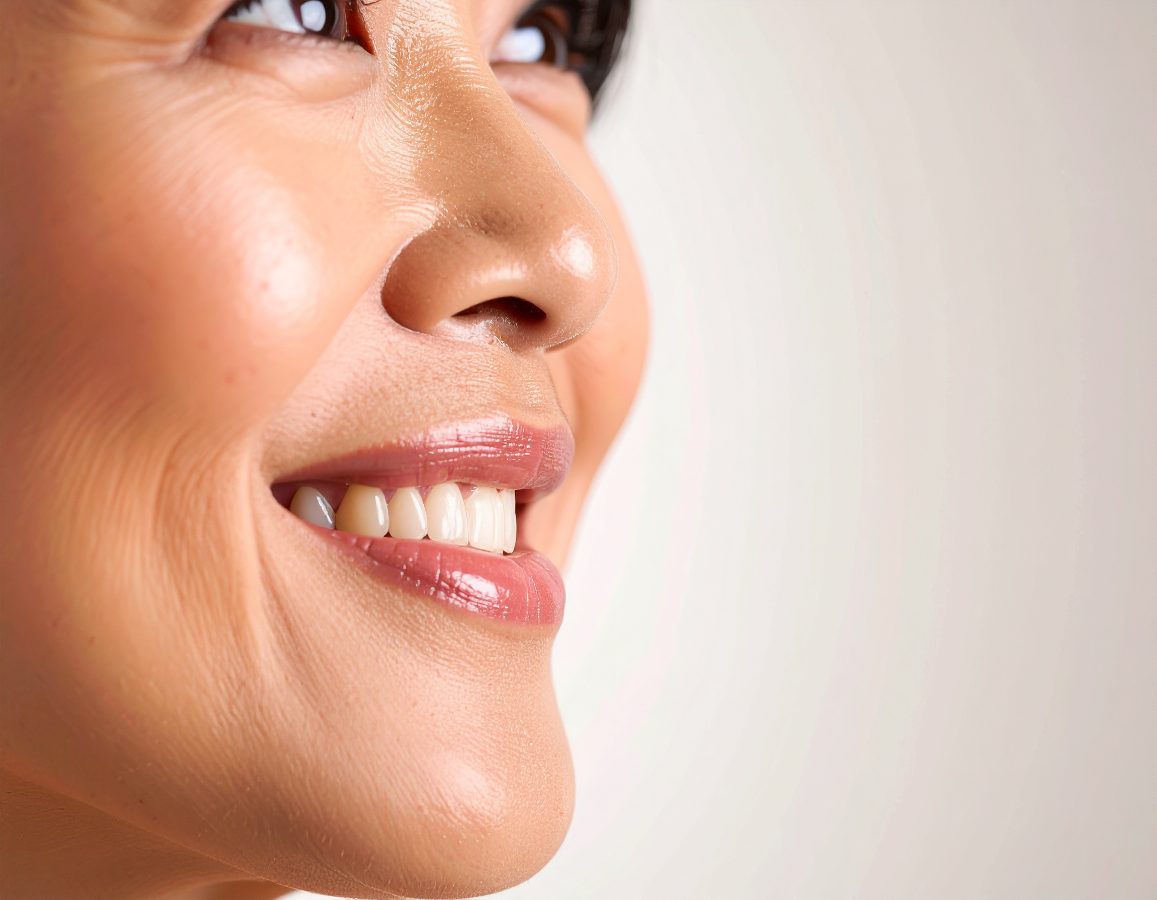 Close-up of a smiling woman's face showcasing smooth skin and white teeth