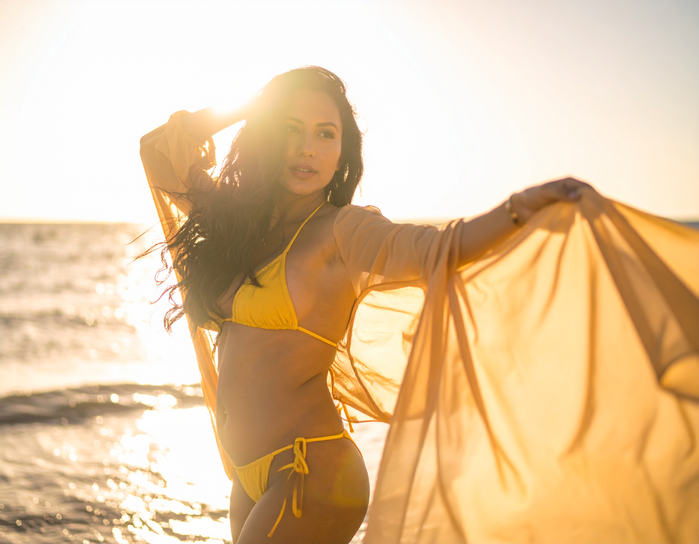 A woman in a bright yellow bikini enjoys a sunny beach day